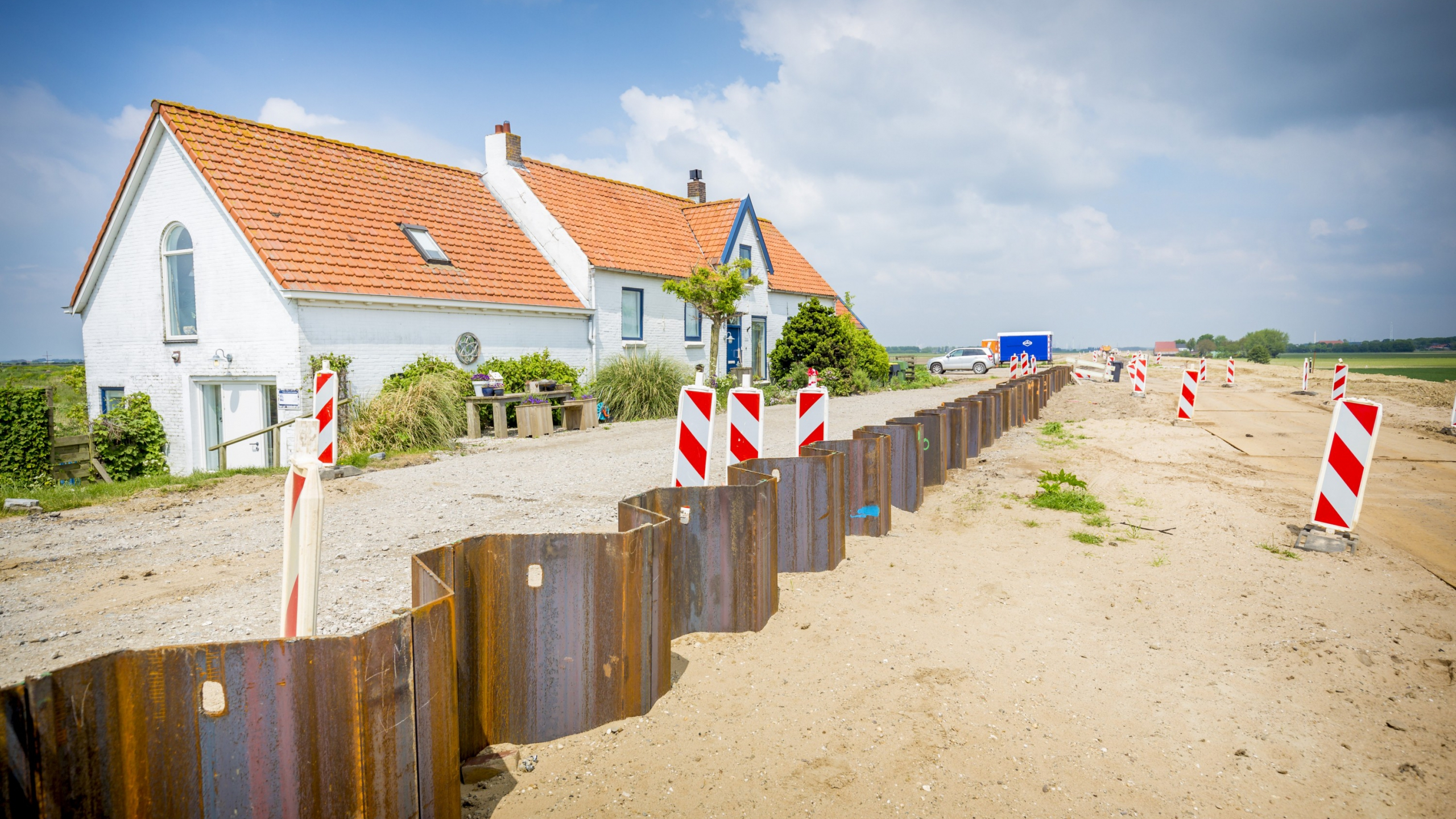 Werkgebied met damwanden en verkeersborden en huis op de achtergrond
