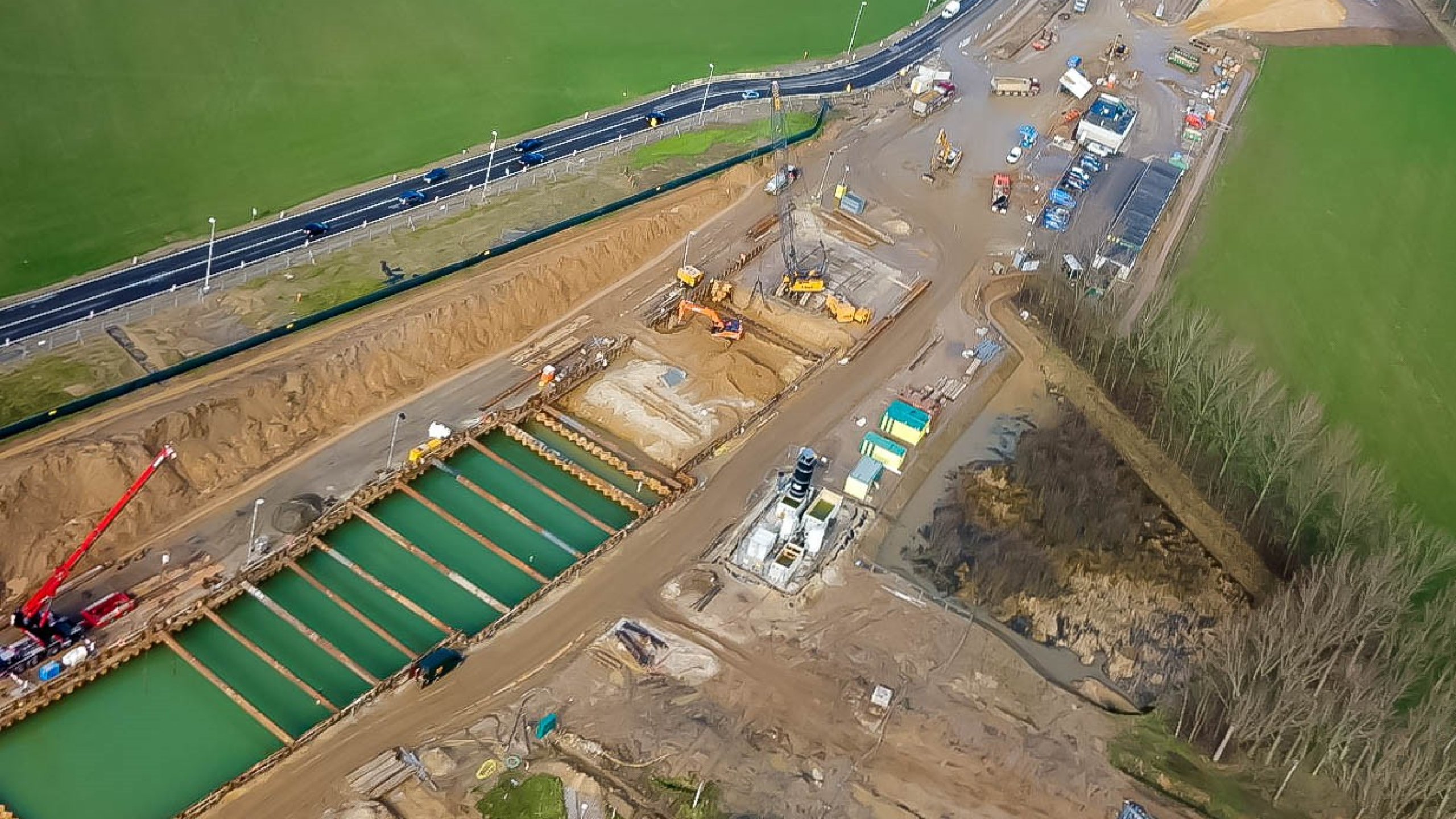 Bovenaanzicht van projectgebied met kranen, vrachtwagens en andere machines