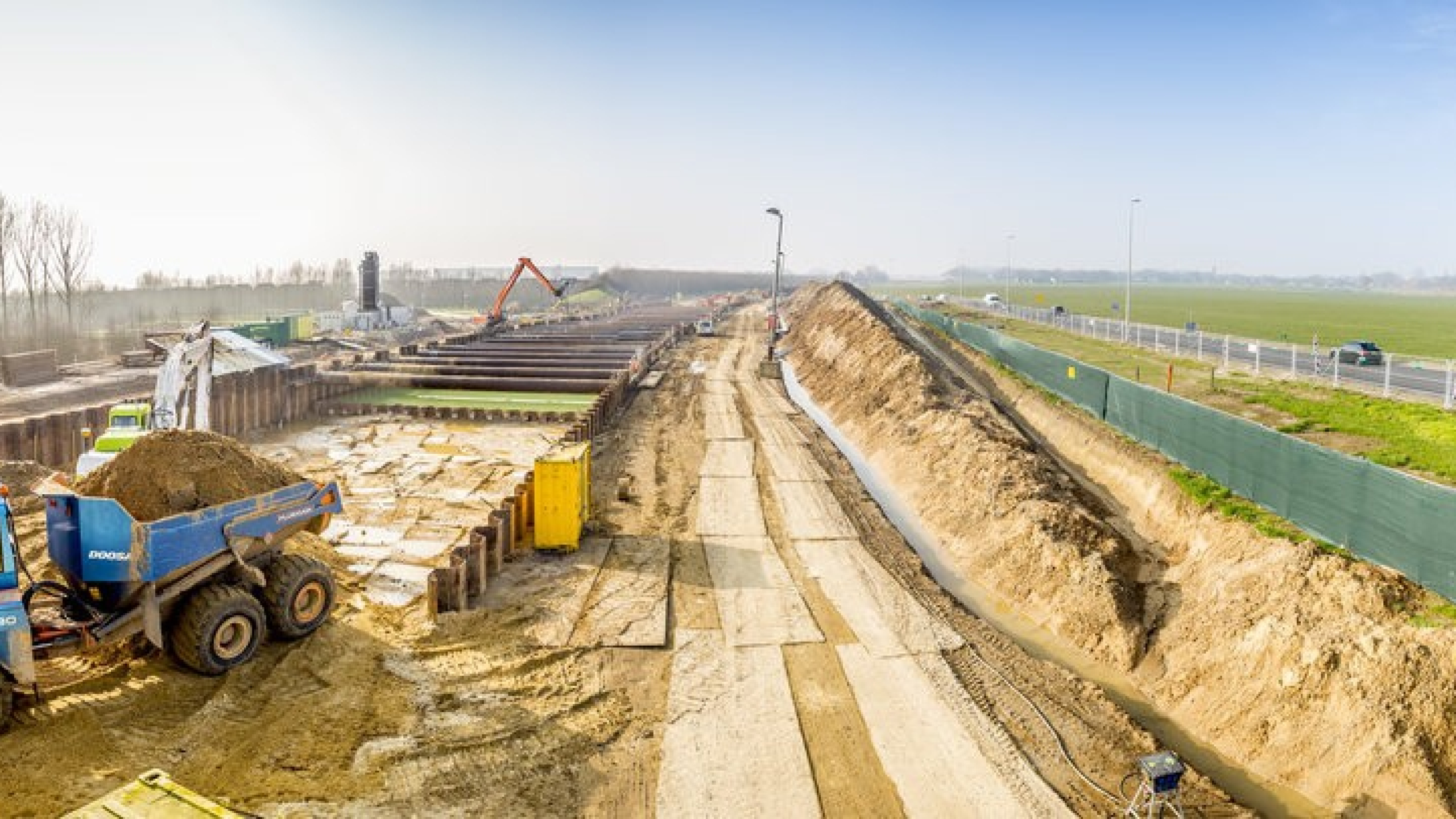 Bouwgebied met een weg van rijplaten en machines aan het werk in het zand