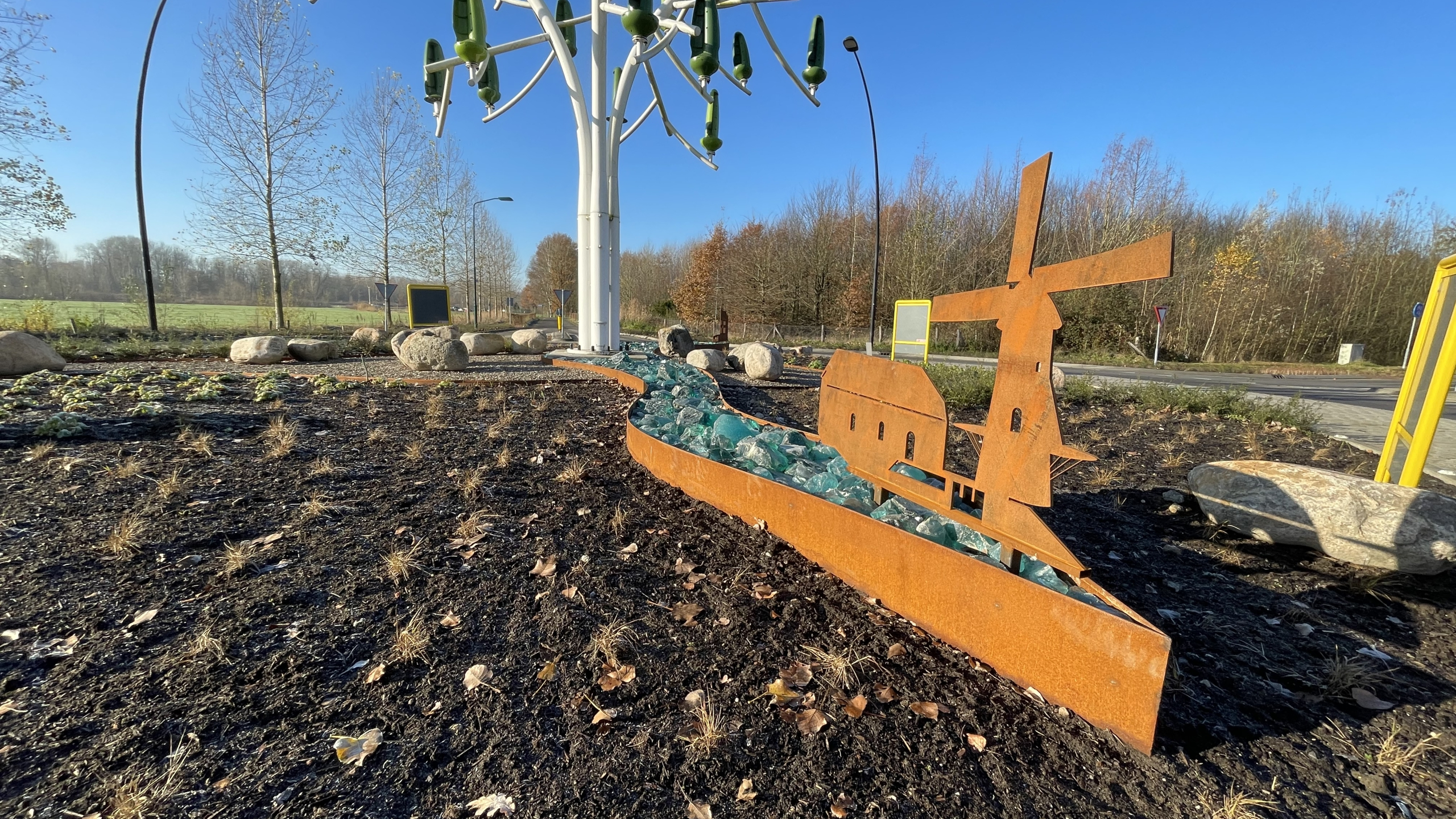 Uitsnede in metaal van molen met de Windenergieboom op de achtergrond
