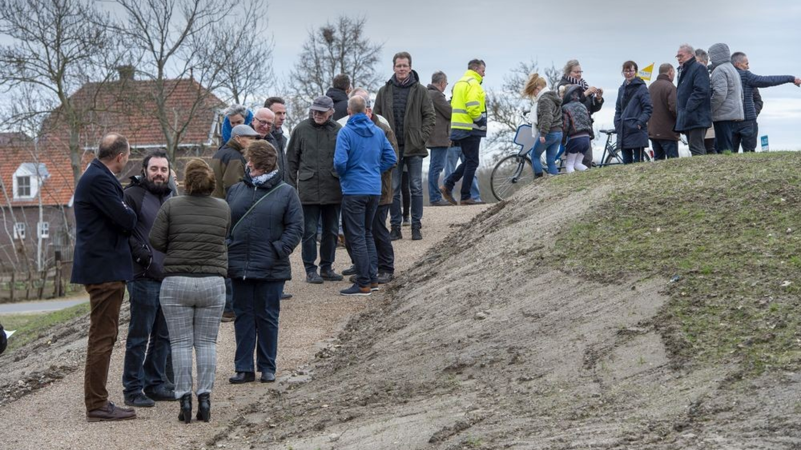 Groep personen staat op een wandelpad op de dijk