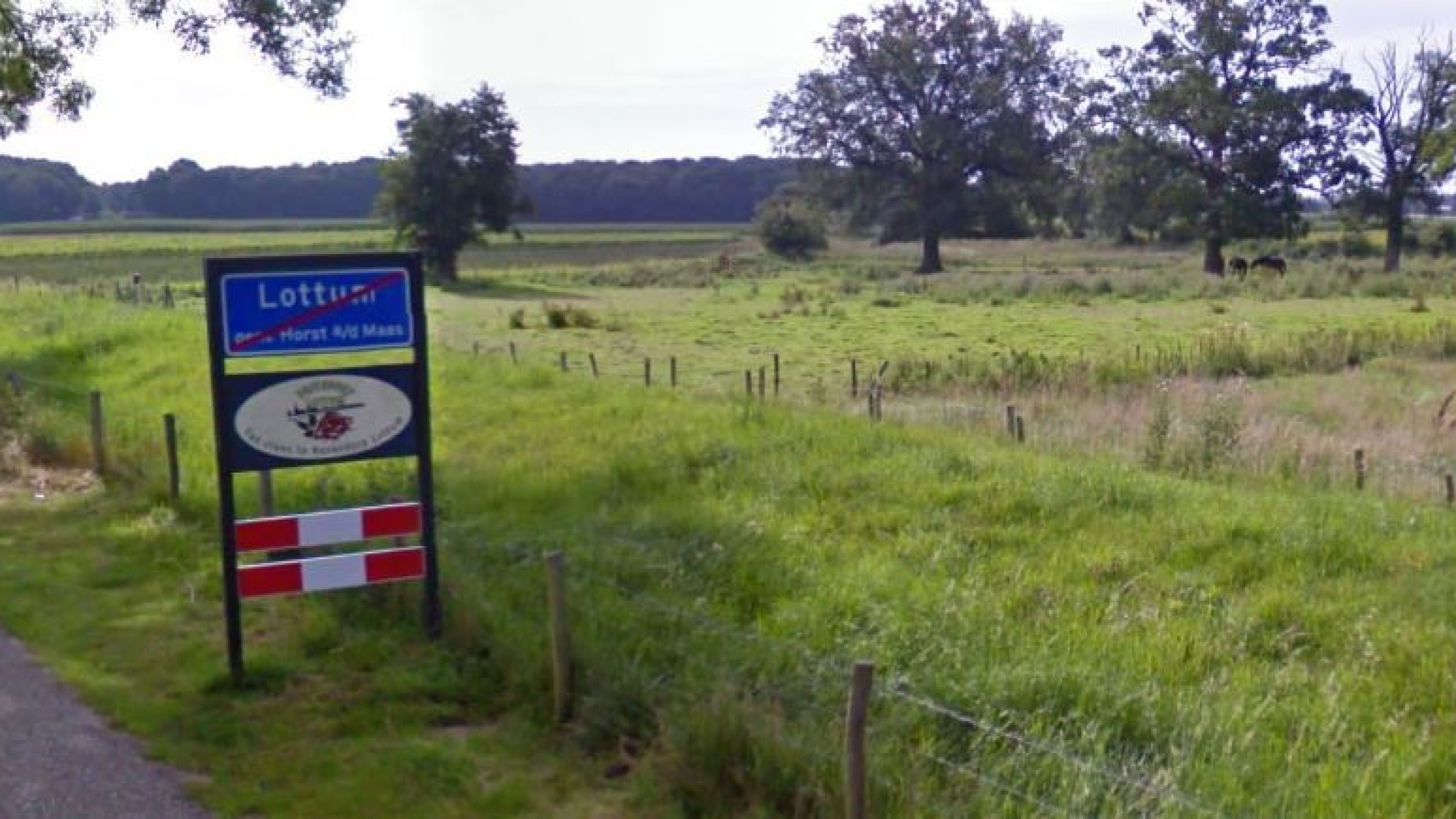 Verkeersbord Lottum naast weg tussen de groene weilanden