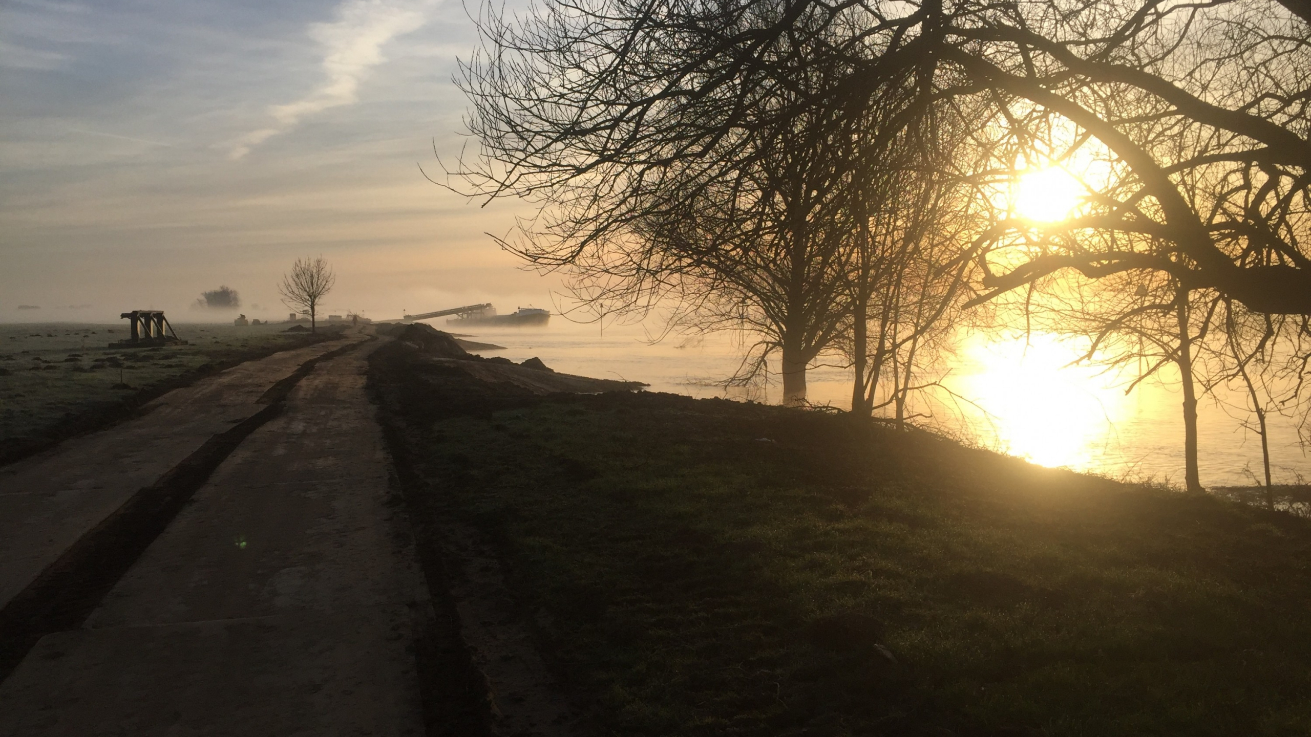 Zonsondergang bij de IJssel met landweg ernaast