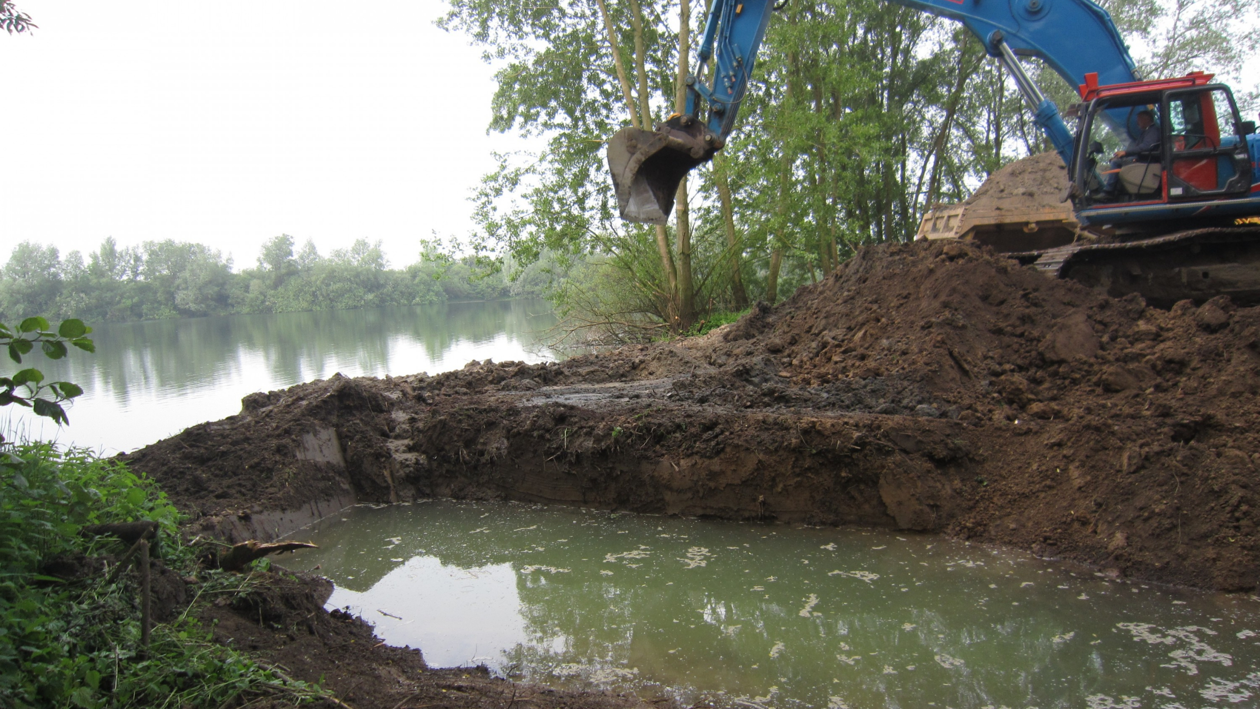Ploegam kraan aan het werk in het zand naast het water