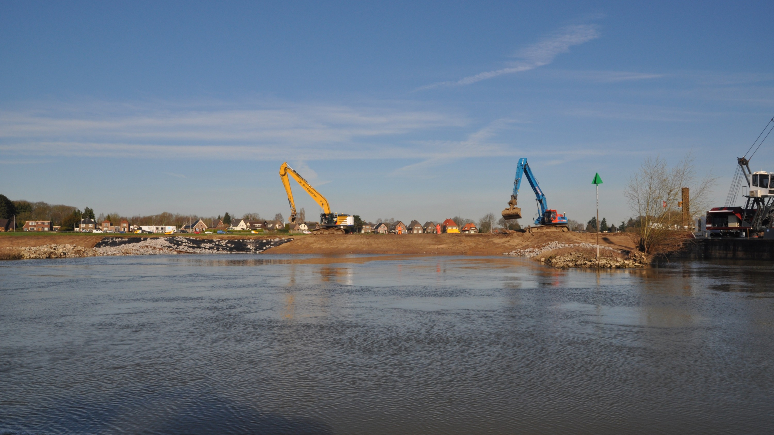 Blauwe Ploegan kraan en gele kraan aan het werk op kade naast het water