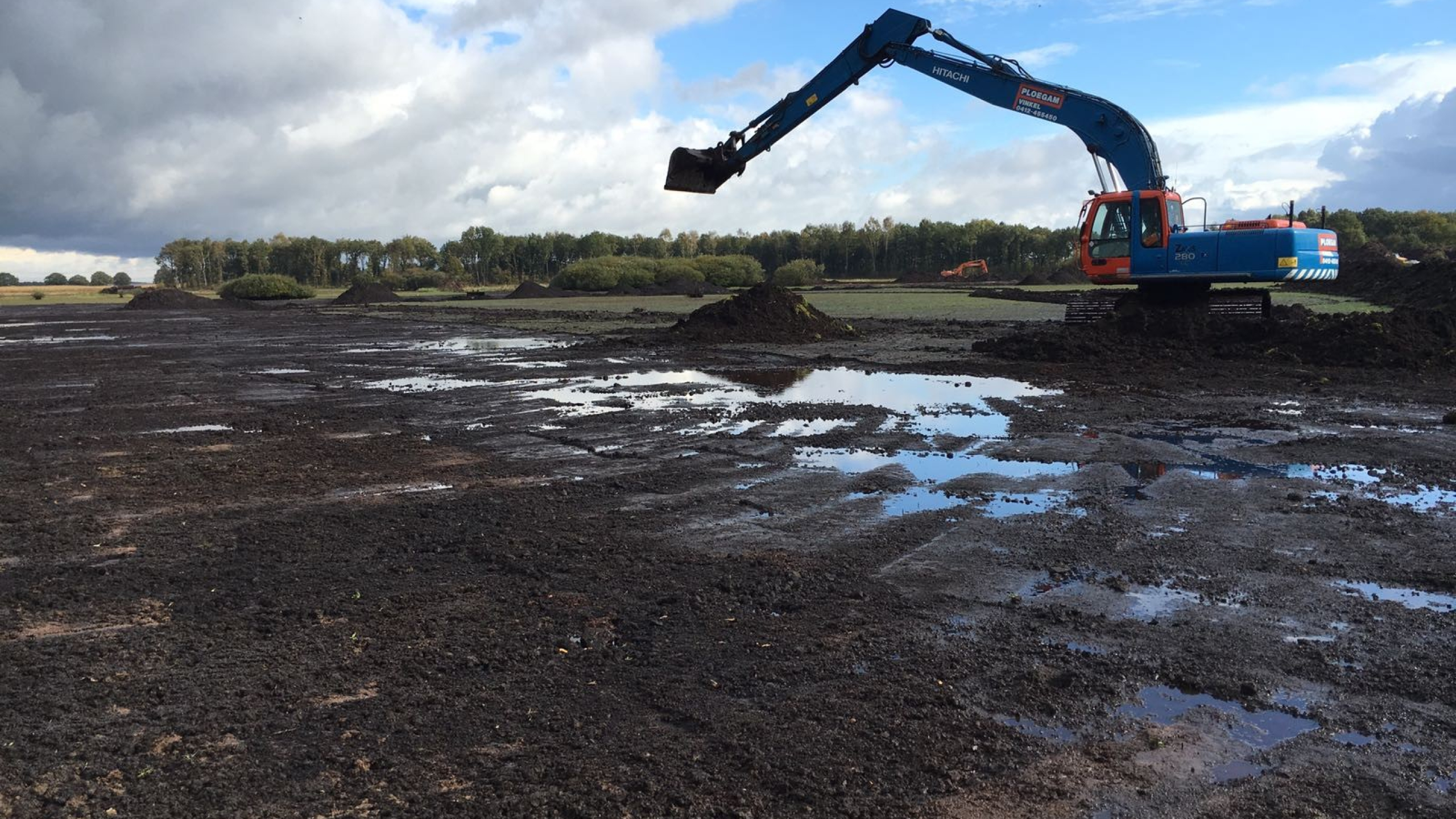 Blauwe Ploegam kraan voert grondwerk uit in nat en modderig gebied