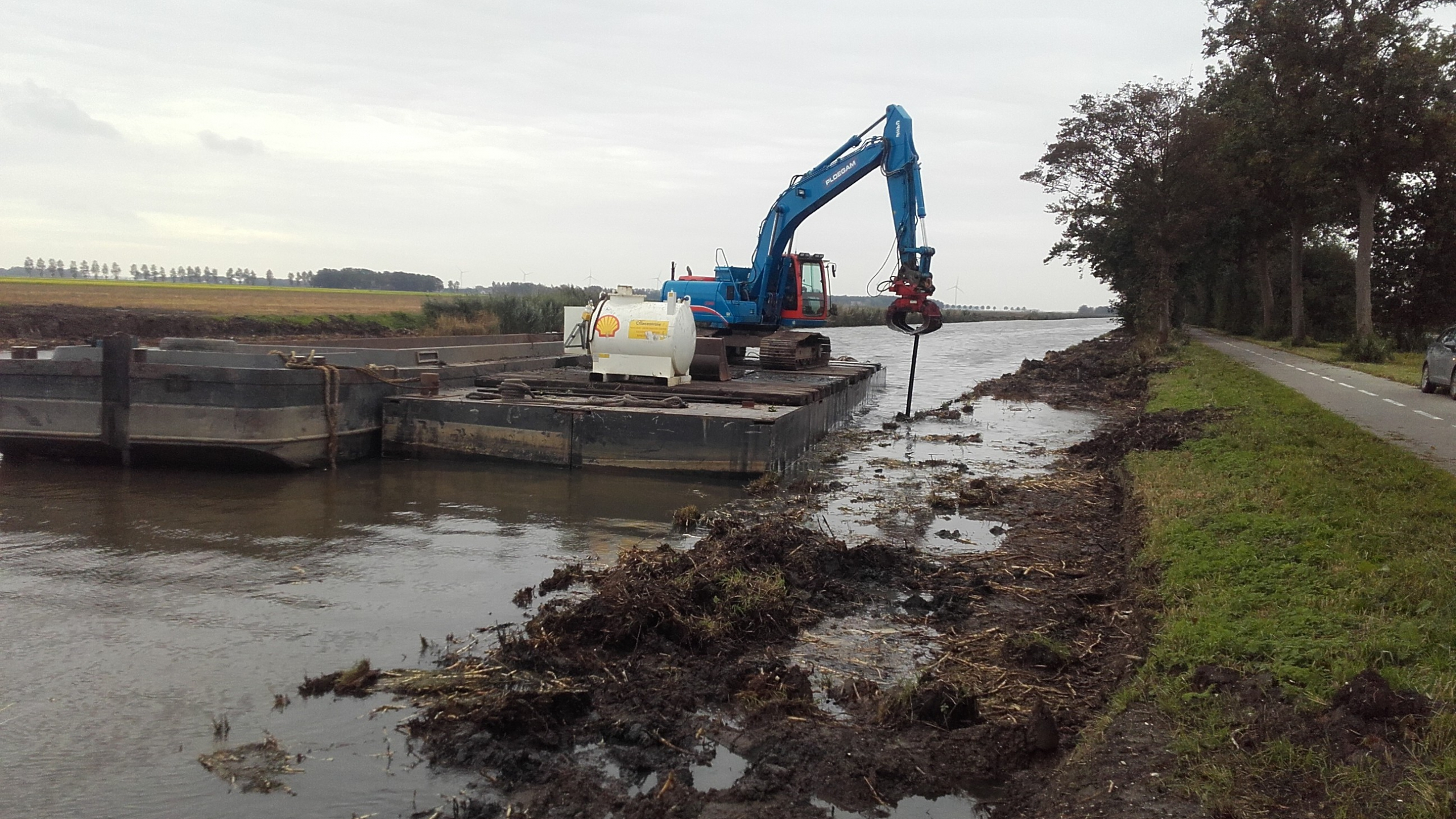 Blauwe Ploegam kraan werkt vanaf ponton op het water