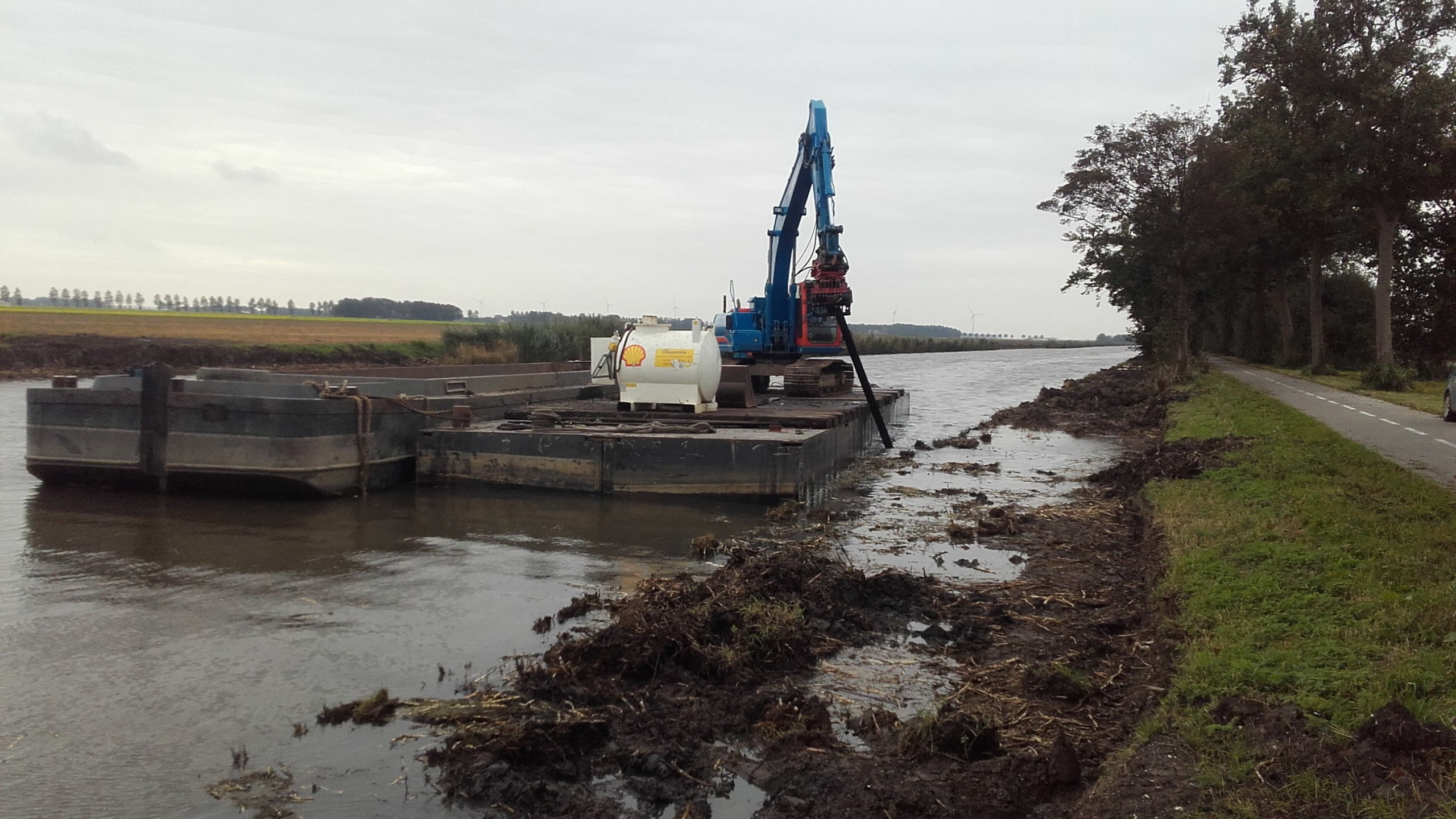 Blauwe Ploegam kraan werkt vanaf ponton op het water
