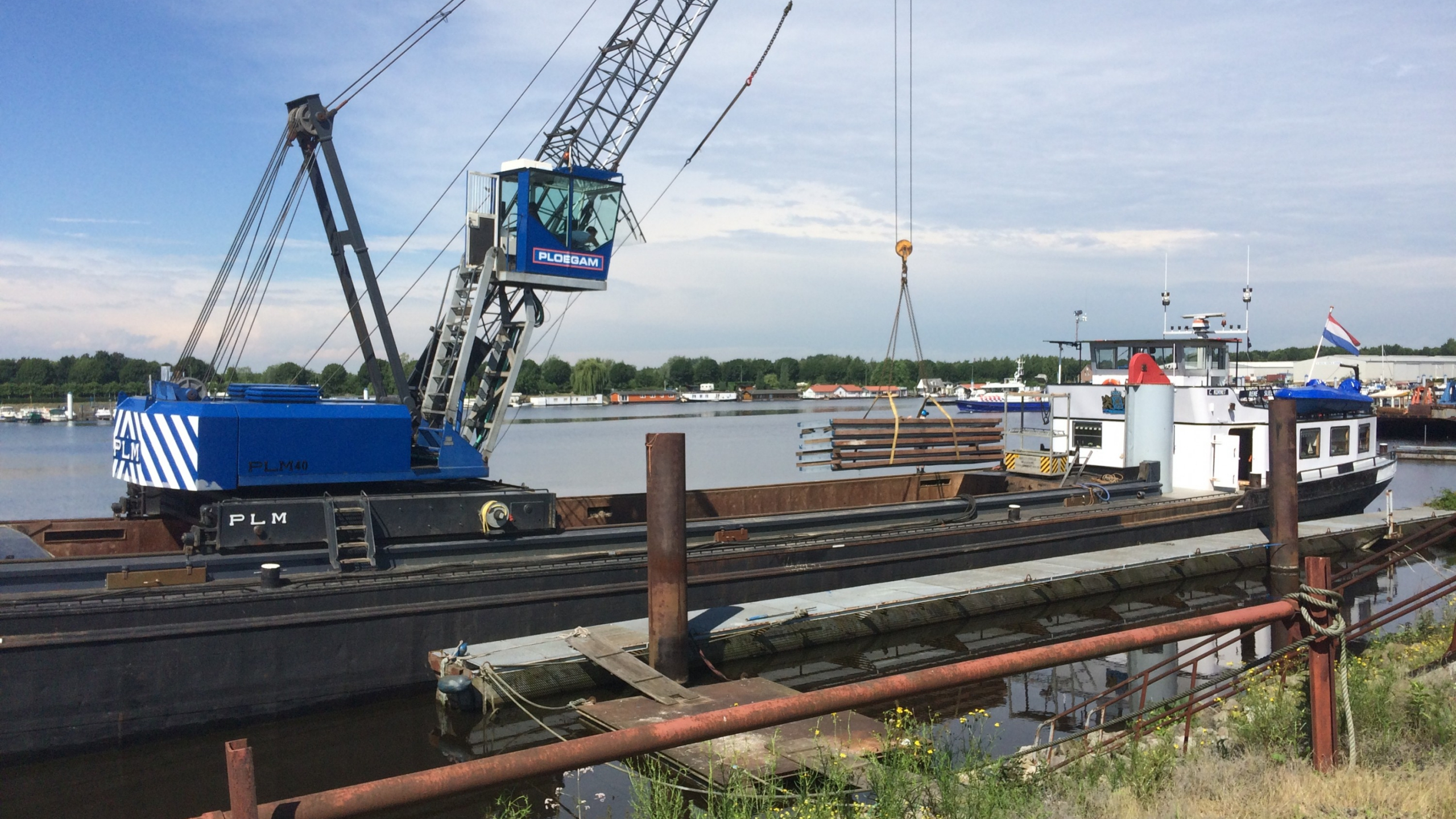 Ploegam kraanmachine plaatst damwanden vanaf een schip