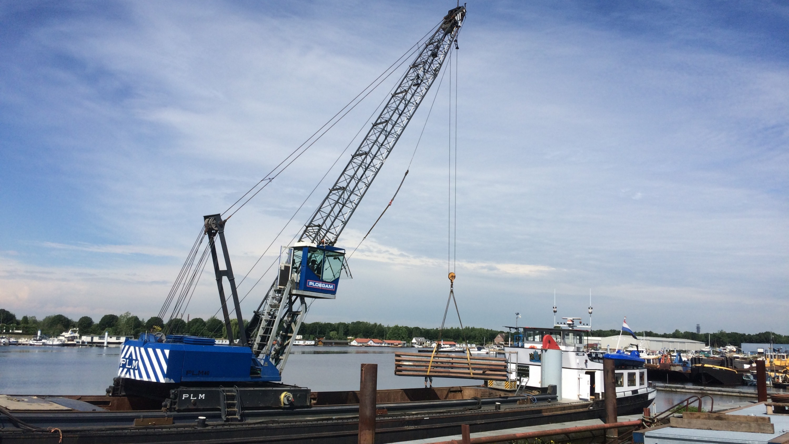 Ploegam kraan plaatst damwanden vanaf een schip