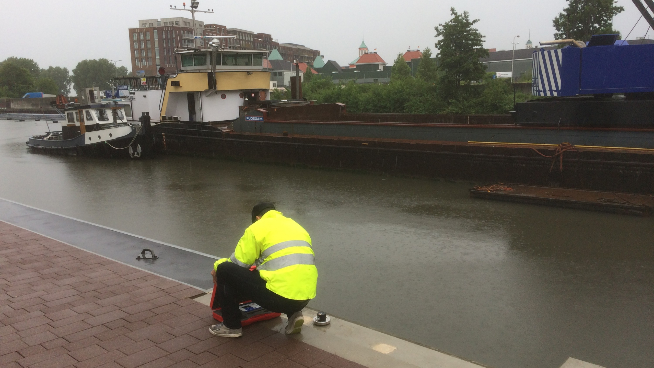 Man met gele veiligheidsjas op de kade van de Maashaven Roermond