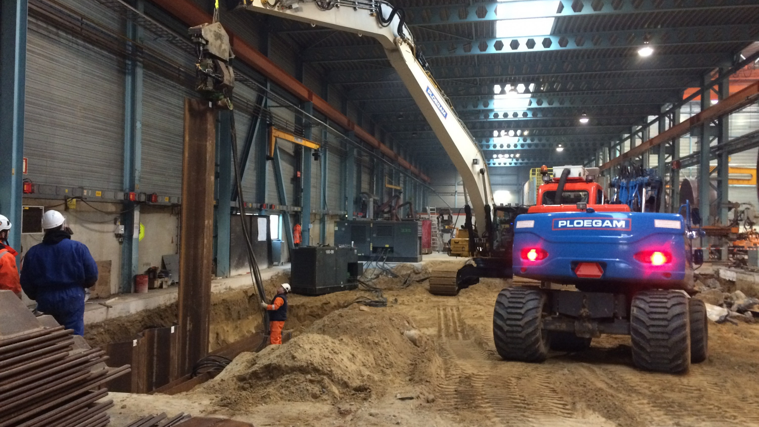 Blauwe Ploegam kraan plaatst damwanden in een loods