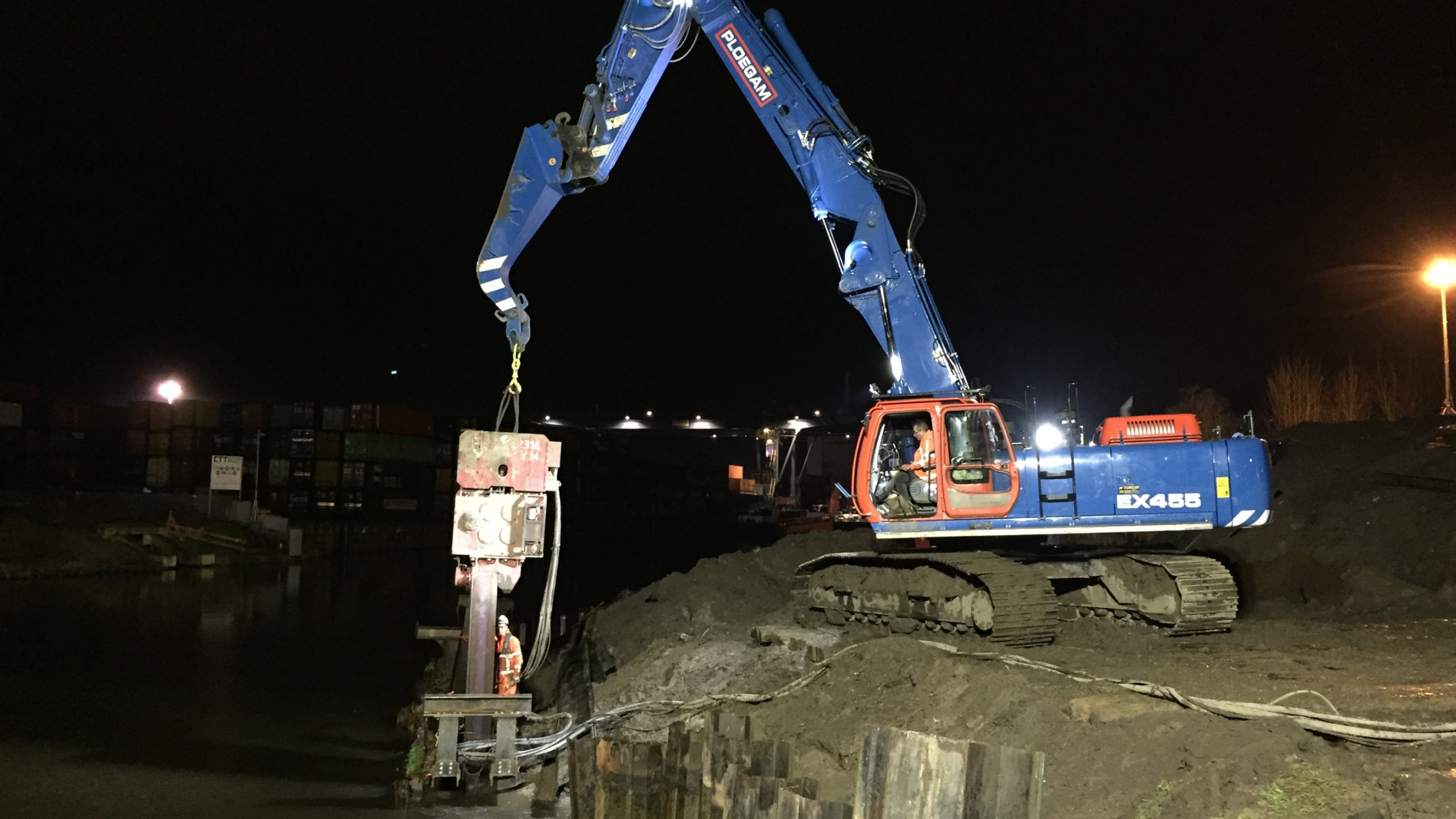 Blauwe Ploegam kraan plaatst damwand in het donker