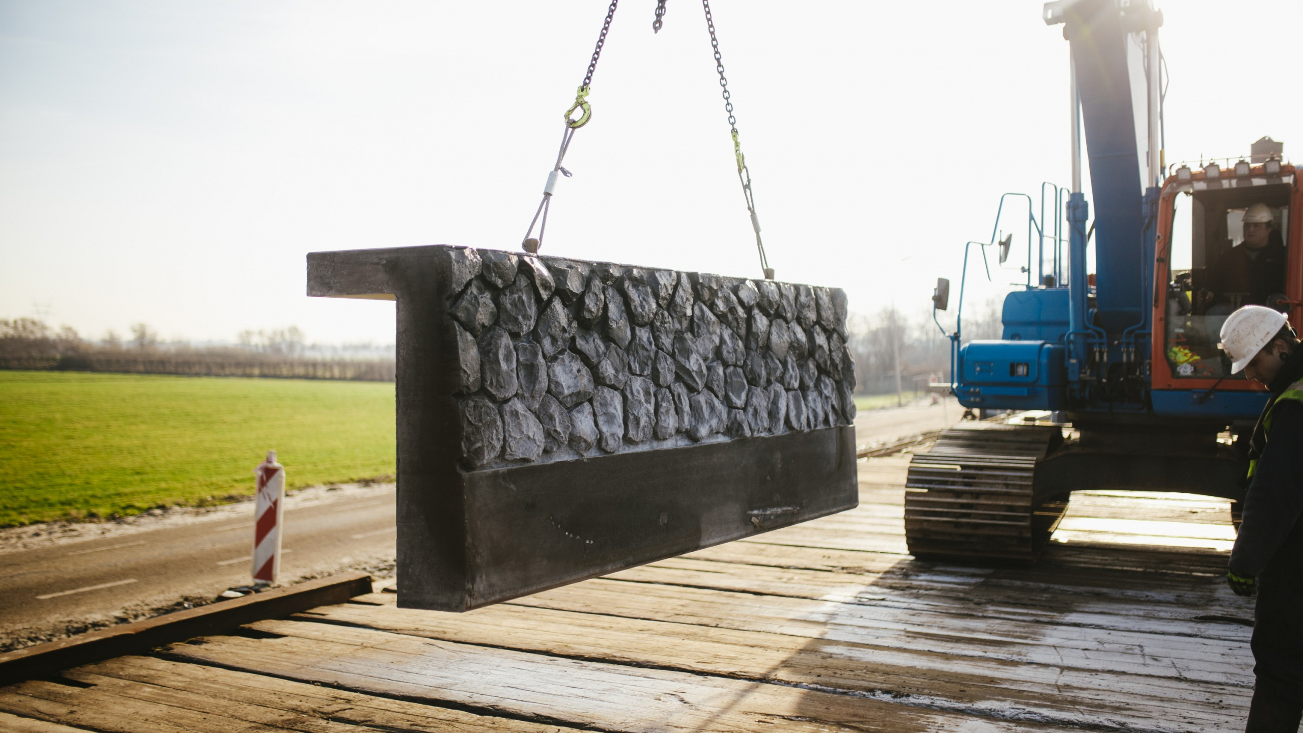 Blauwe Ploegam kraan hijst beton met stenen over de kade in de Boterhuispolder