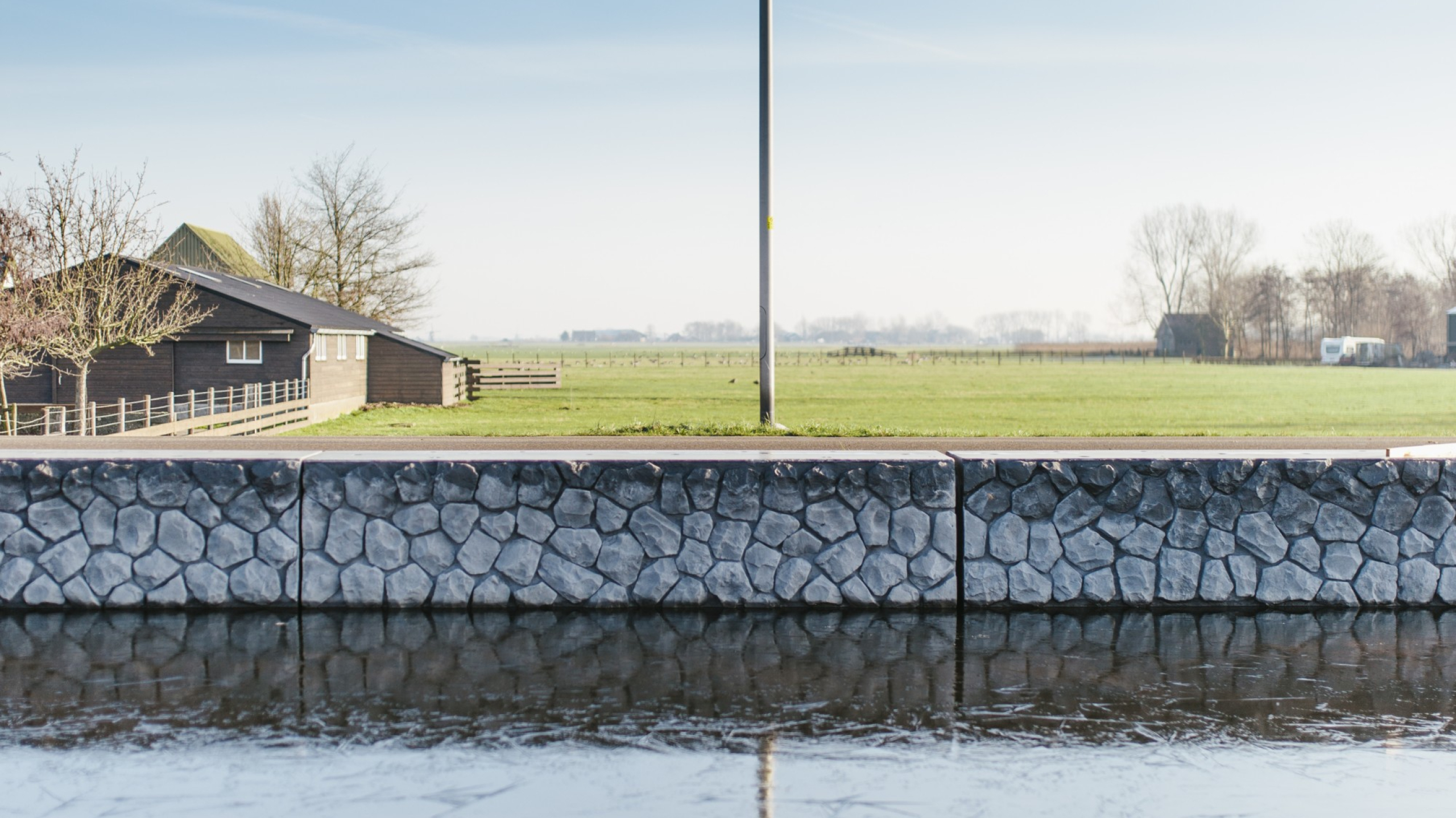 Kade van stenen met weilanden op de achtergrond in de Boterhuispolder