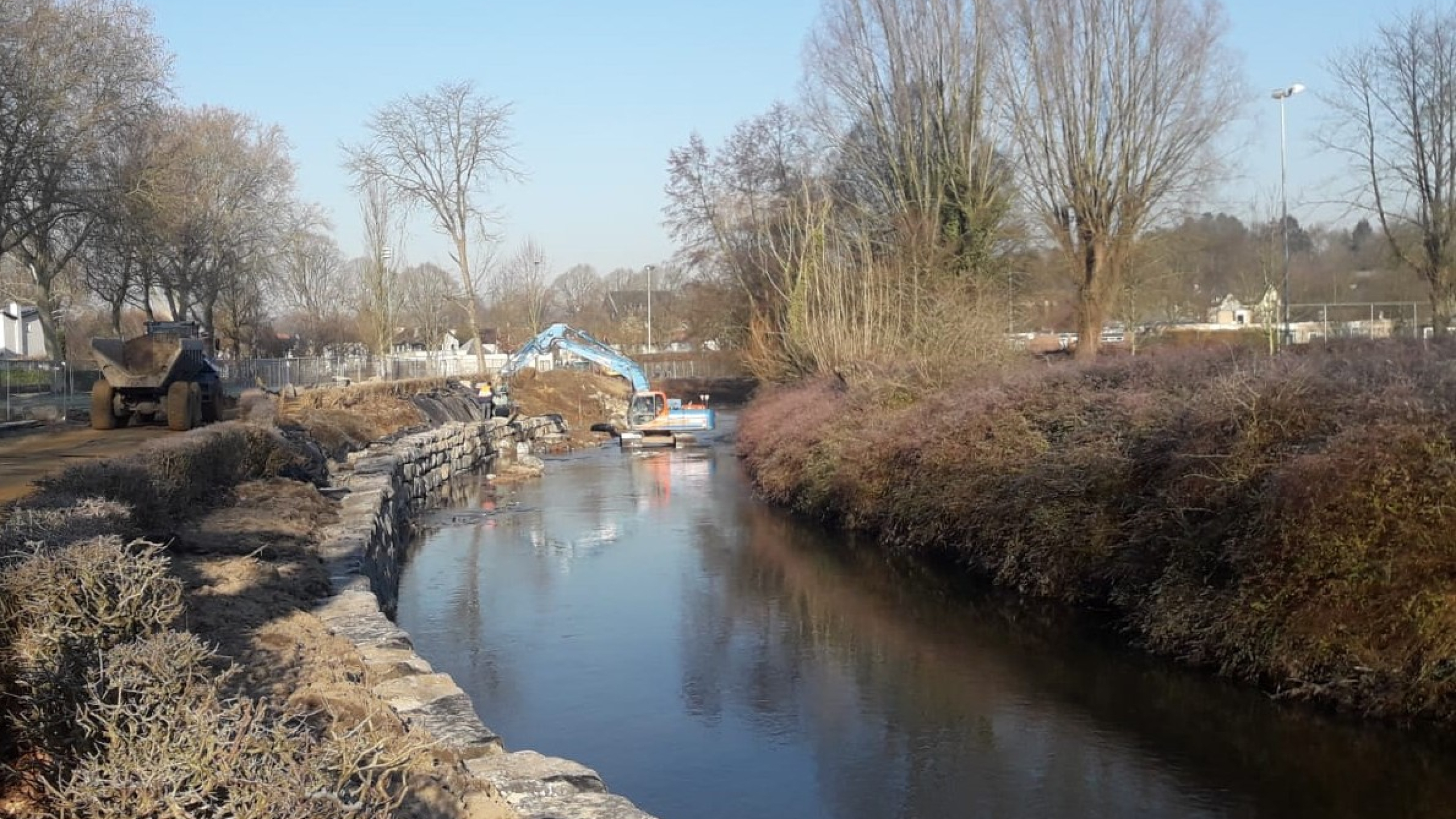 Ploegam kraan aan het werk aan stapelmuur van stenen in de Geul in Valkenburg