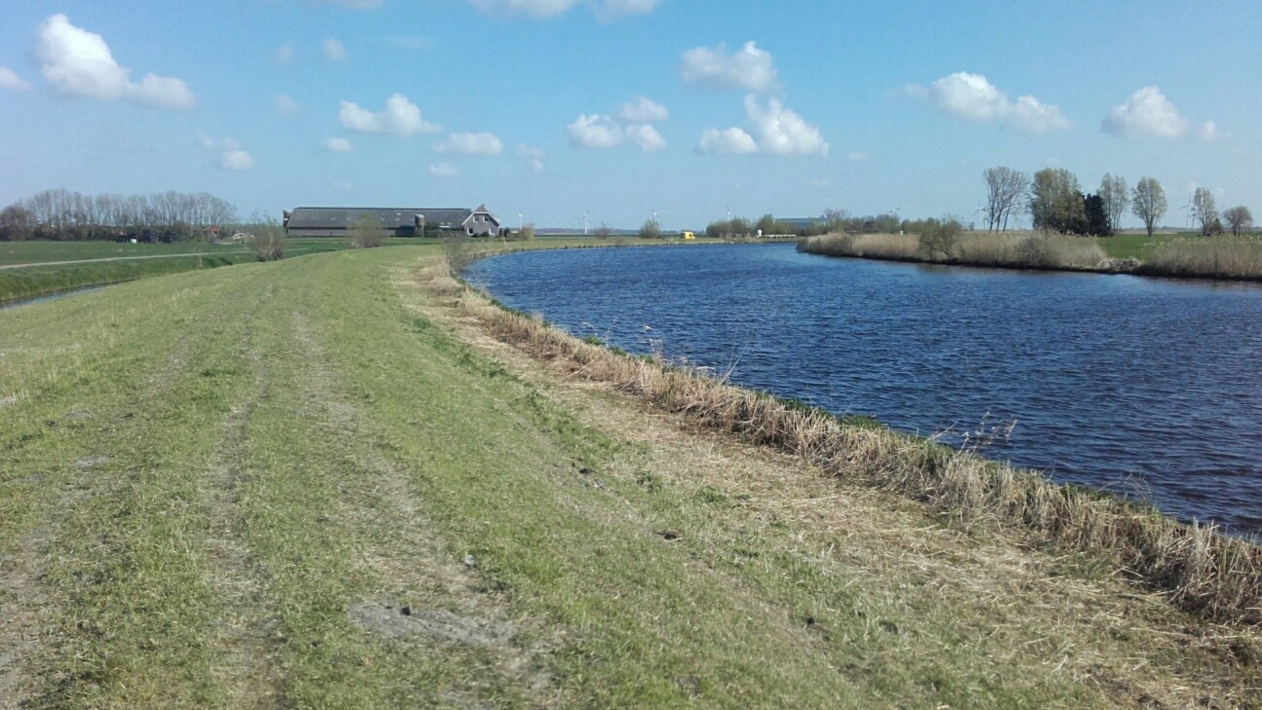 Rivier met groen weiland en boerderij op de achtergrond bij de Maatpolderkade