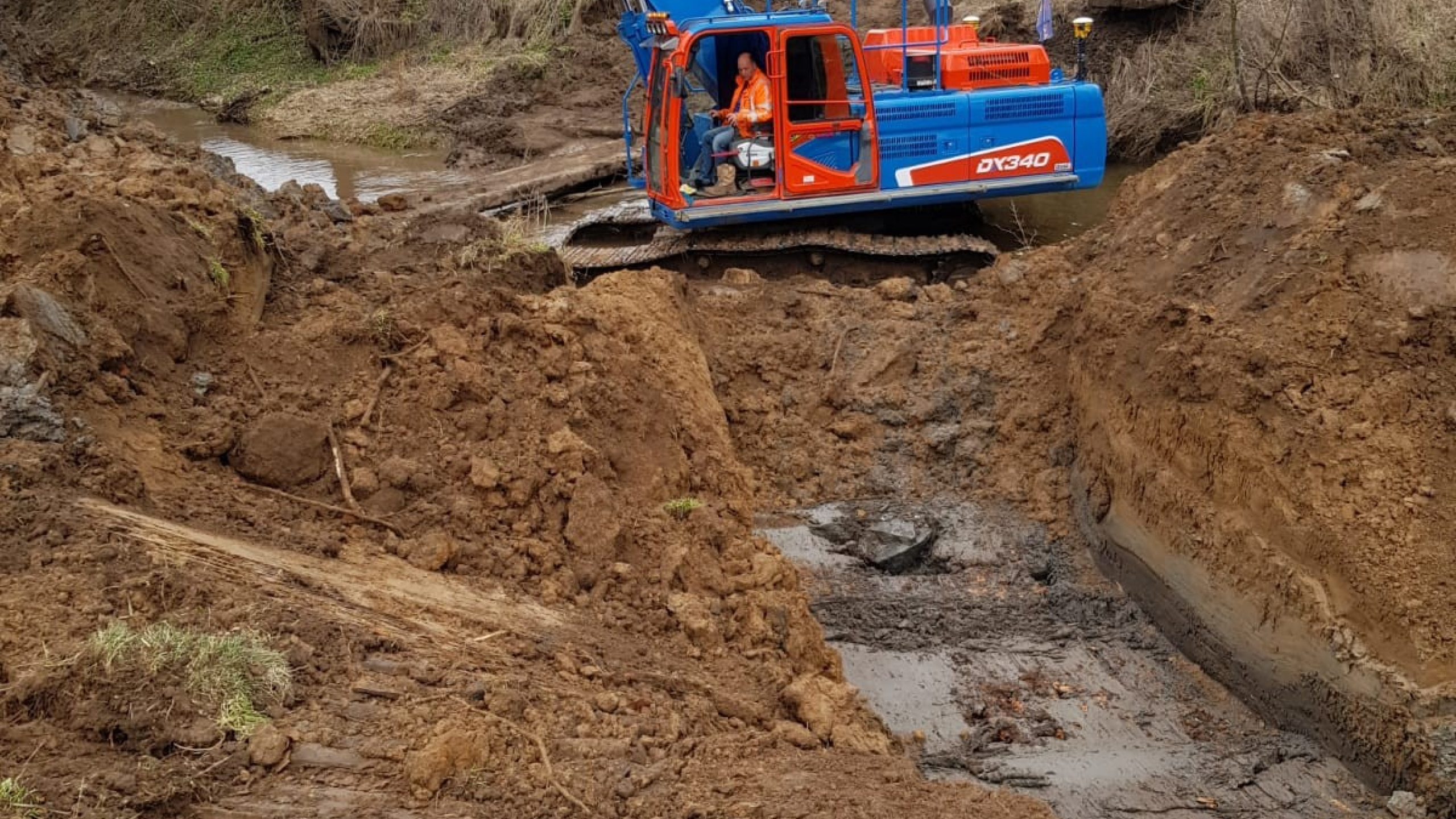 Blauwe Ploegam kraan aan het werk met grondwerkzaamheden in het zand 