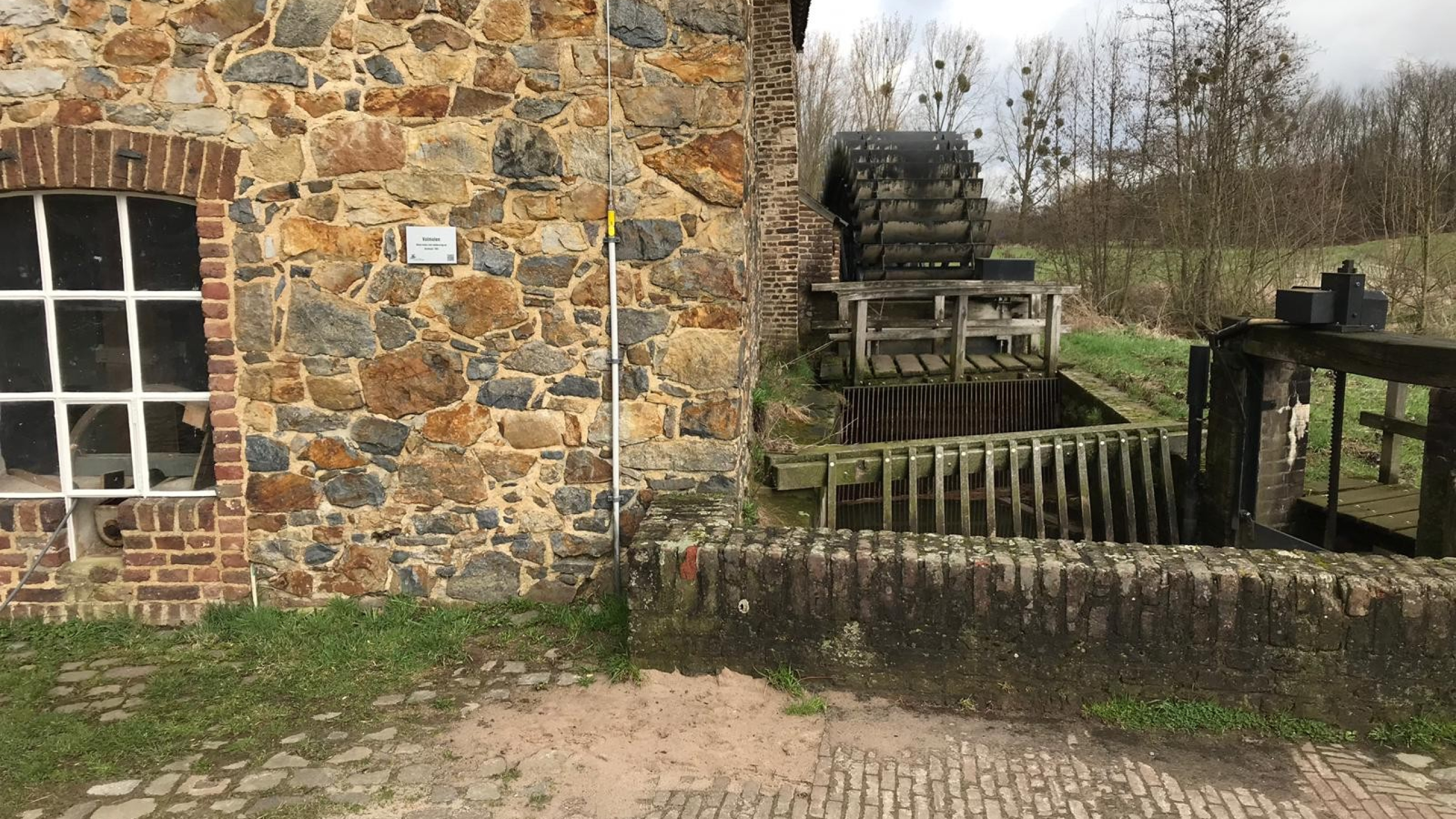  Naast een gebouw met bruine stenen staat de Volmolen in Epen