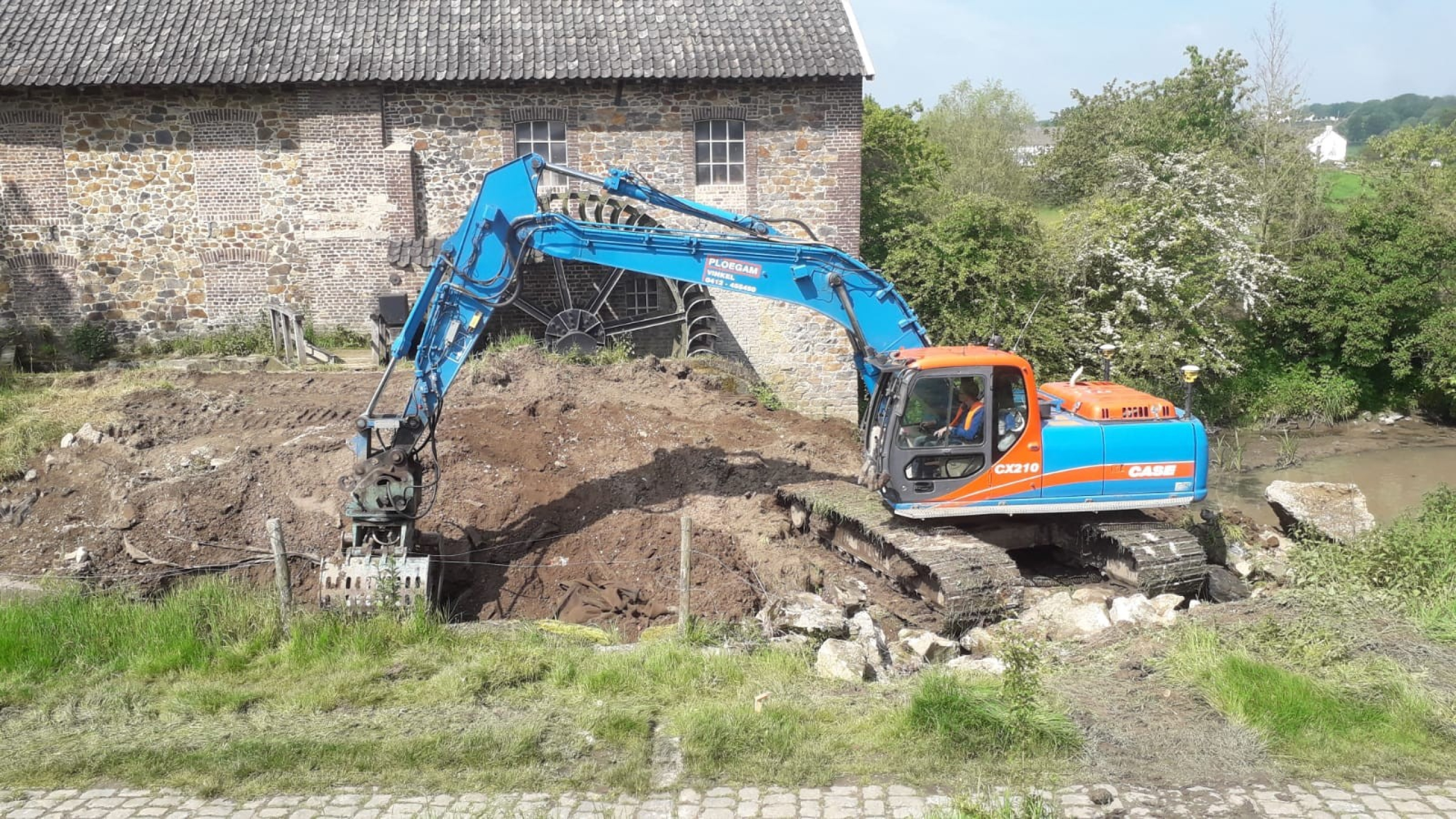 Blauwe Ploegam kraan aan het werk met grondwerkzaamheden naast Volmolen in Epen