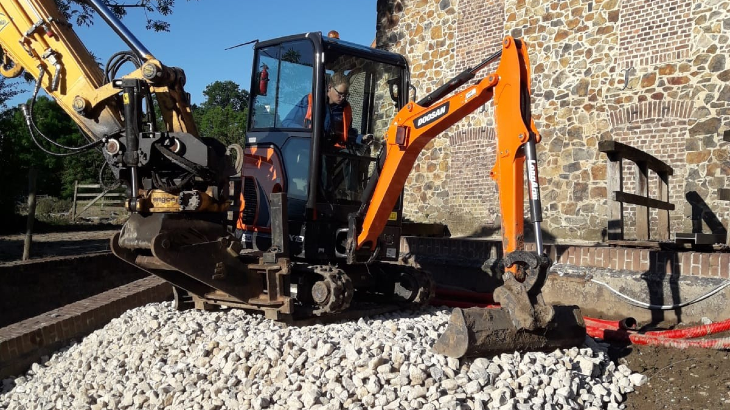 Oranje graafmachine schept grijze stenen