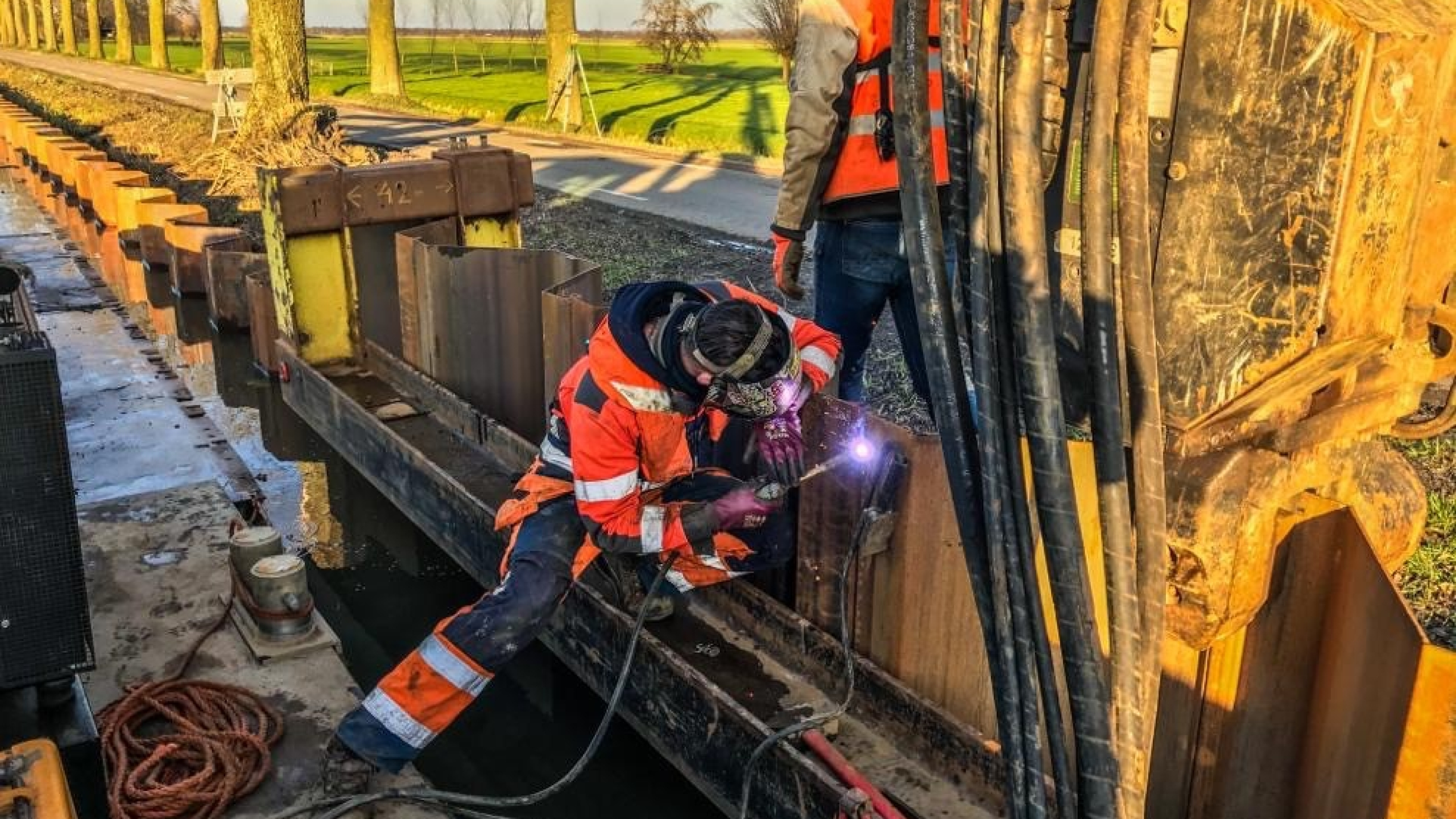 Man met veiligheidskleding last damwanden aan elkaar met een lasapparaat