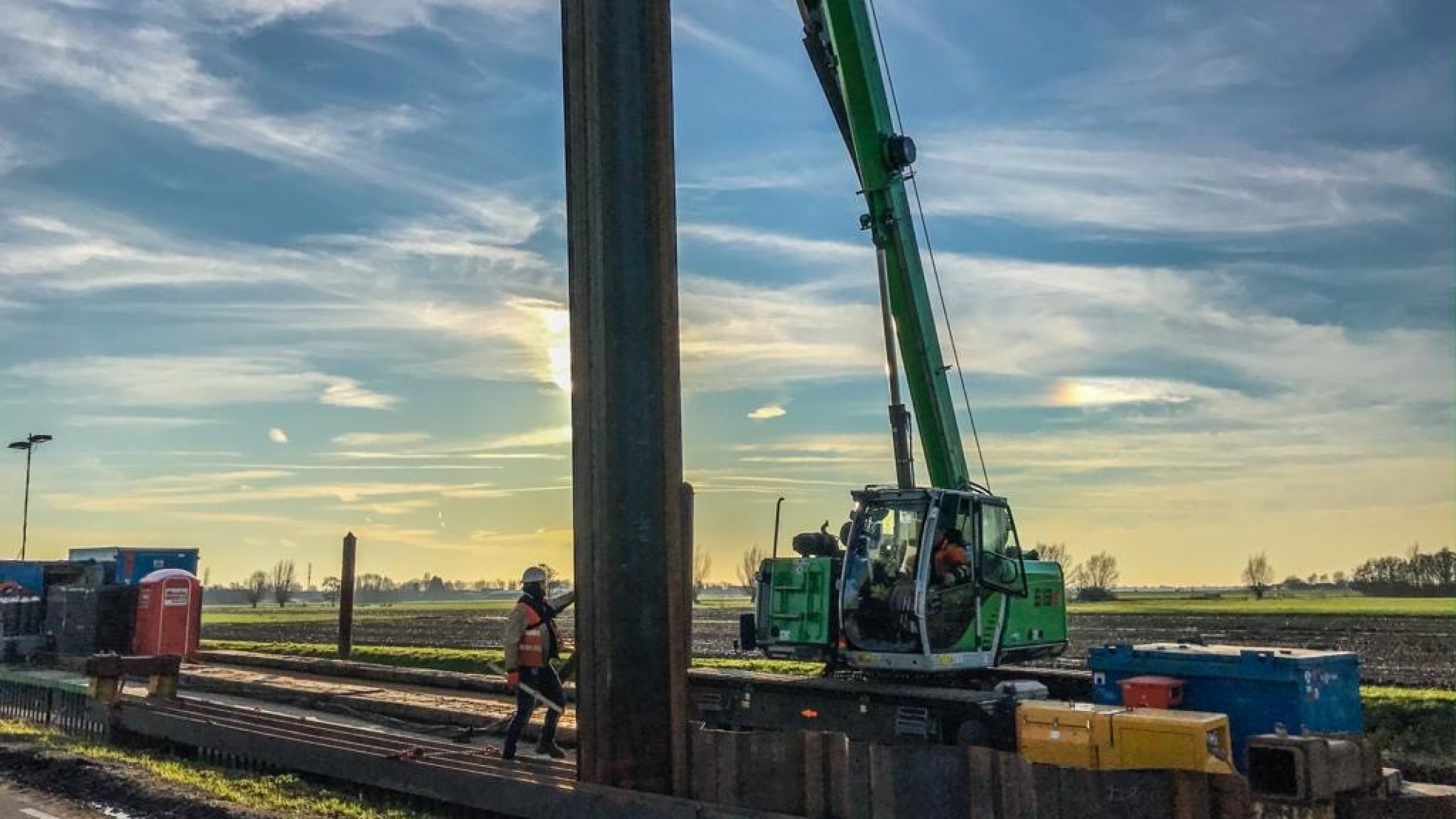 Groene kraan hijst vanaf ponton op het water damwanden in de Montfoortsevaartkade