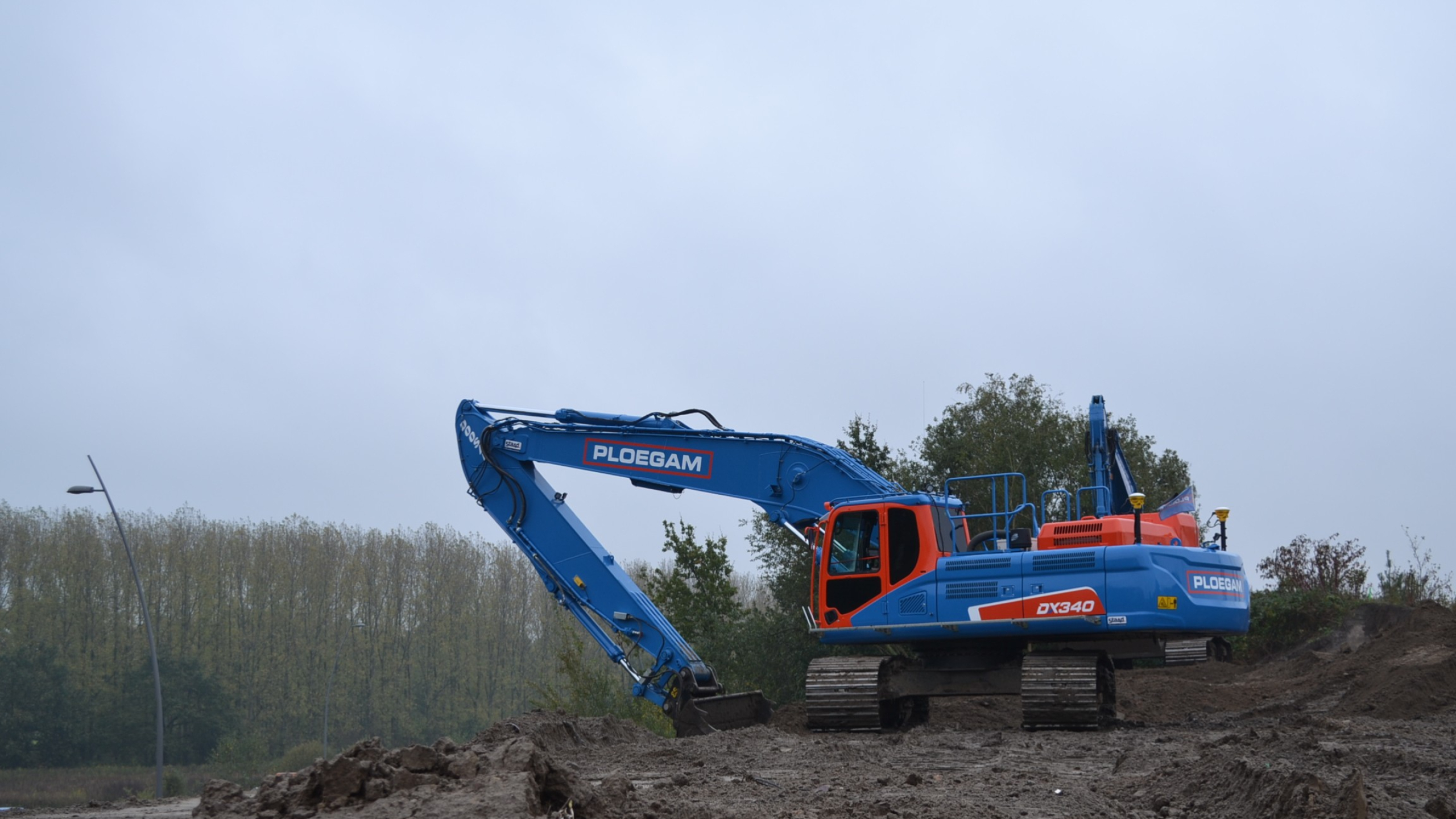 Blauwe Ploegam kraan op een hoop zand met een grijze lucht