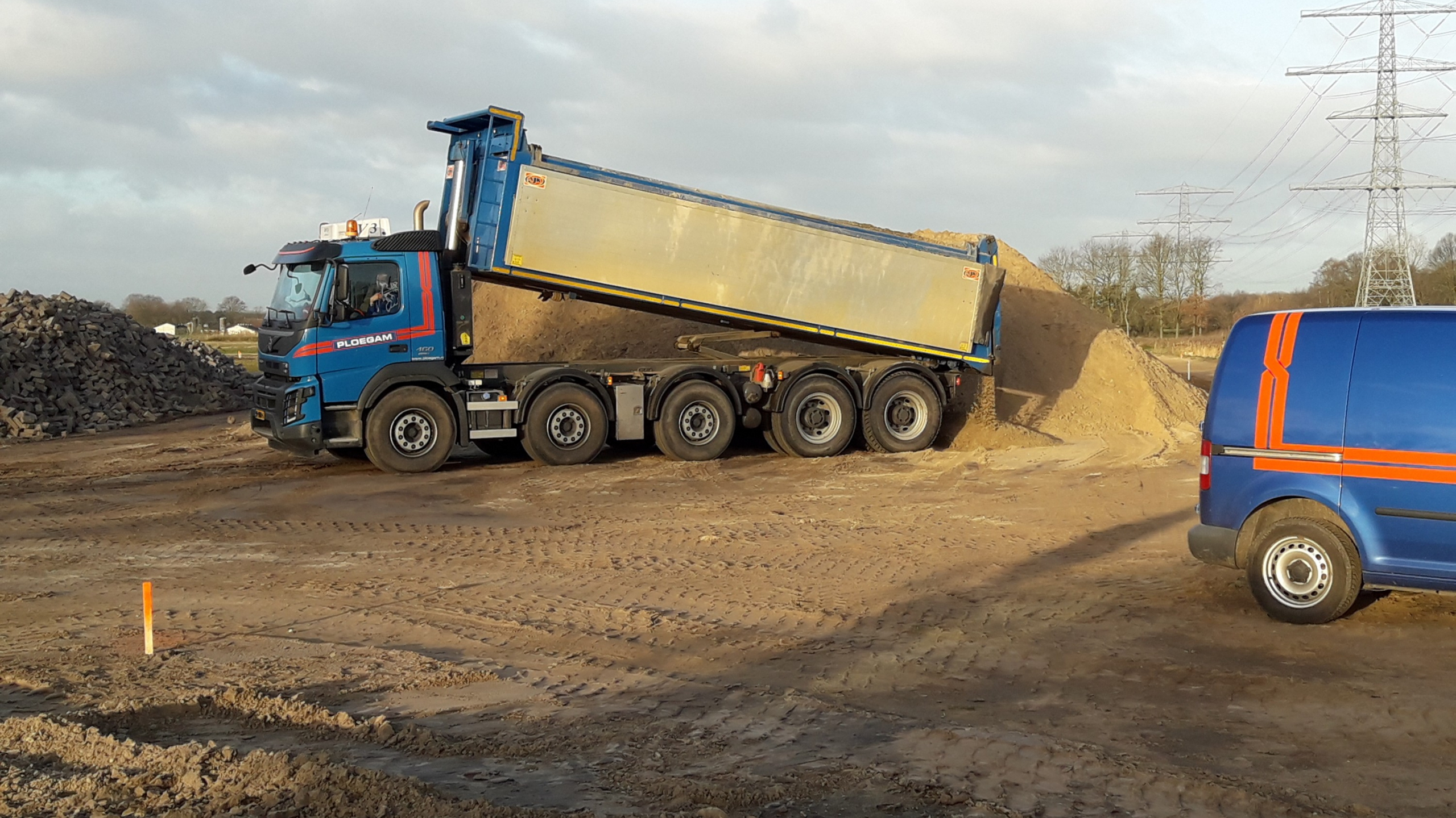 Ploegam vrachtwagen kiept zand op het werkgebied