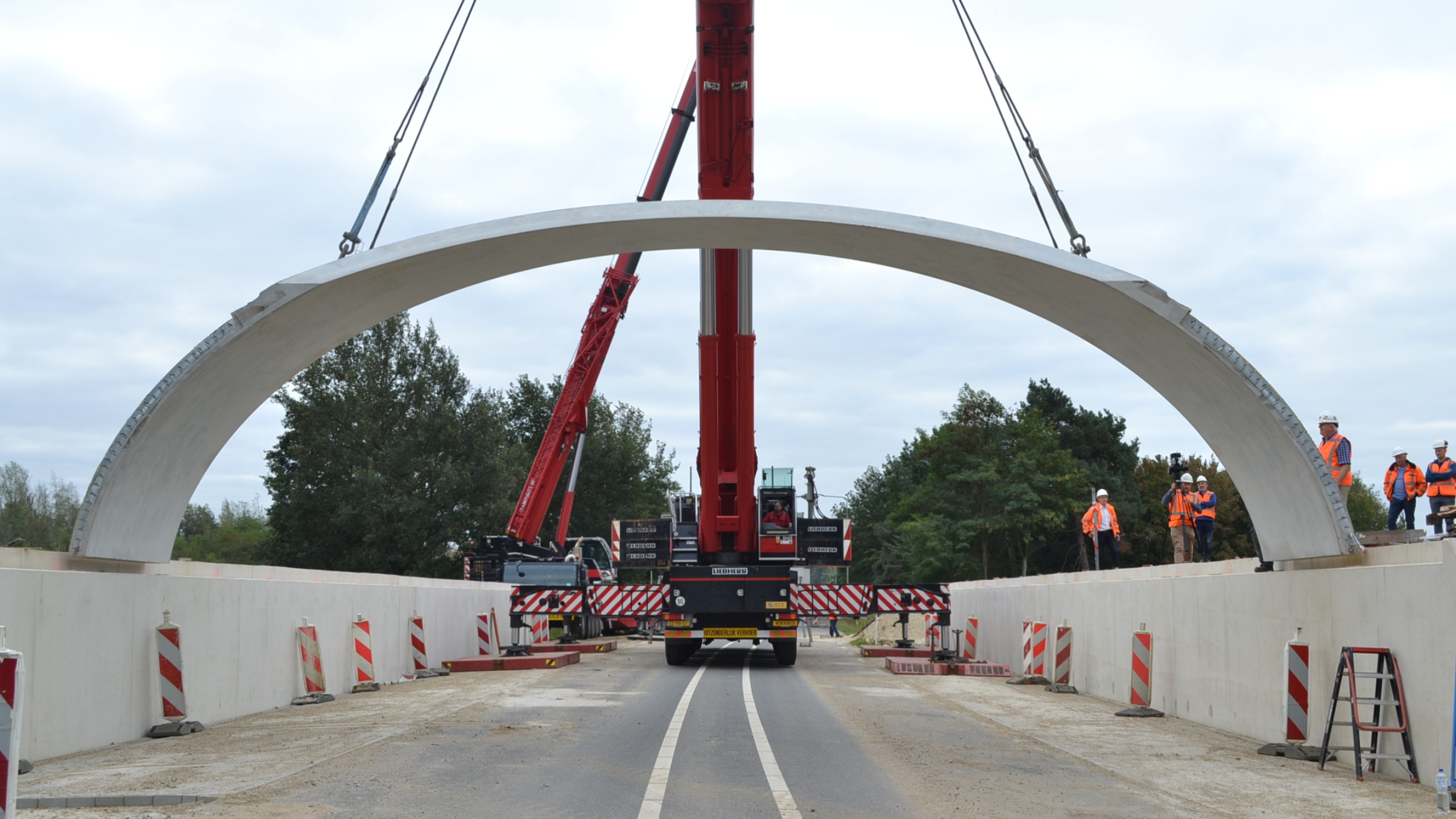 Rode kraan plaatst betonnen koepel bij ecoduct