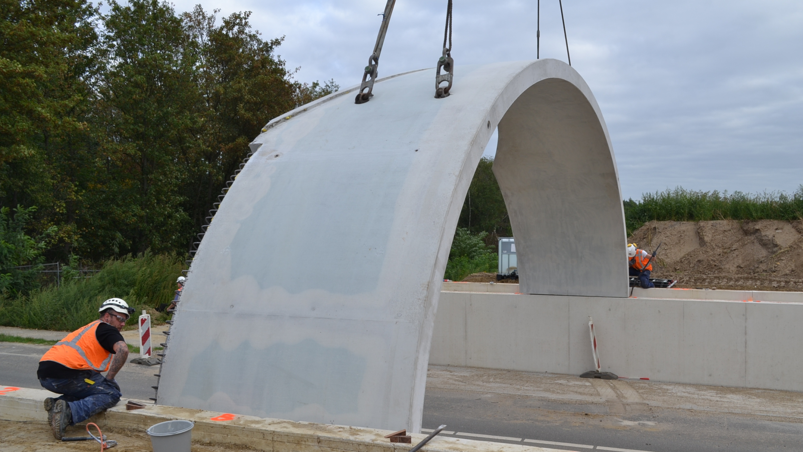 Mannen met veiligheidshesjes en helmen plaatsen van een betonnen koepel