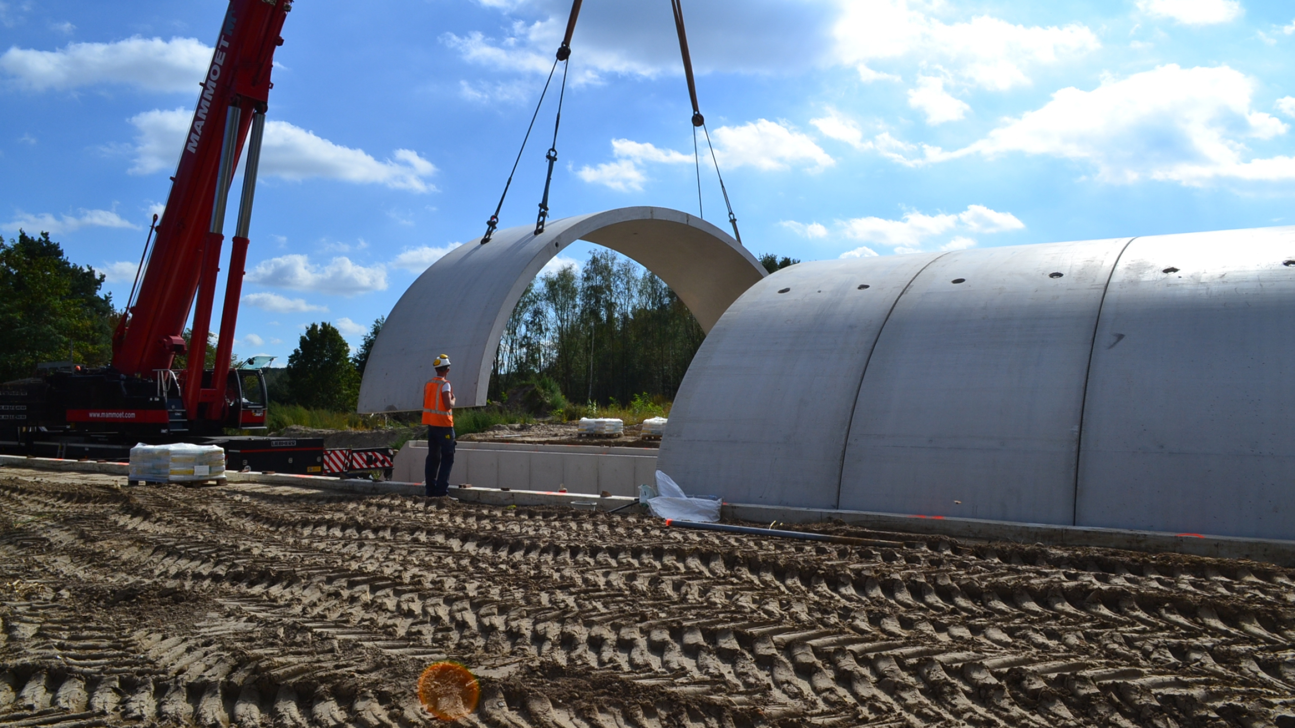 Man met veiligheidshesje kijkt toe bij het plaatsen van ecoduct