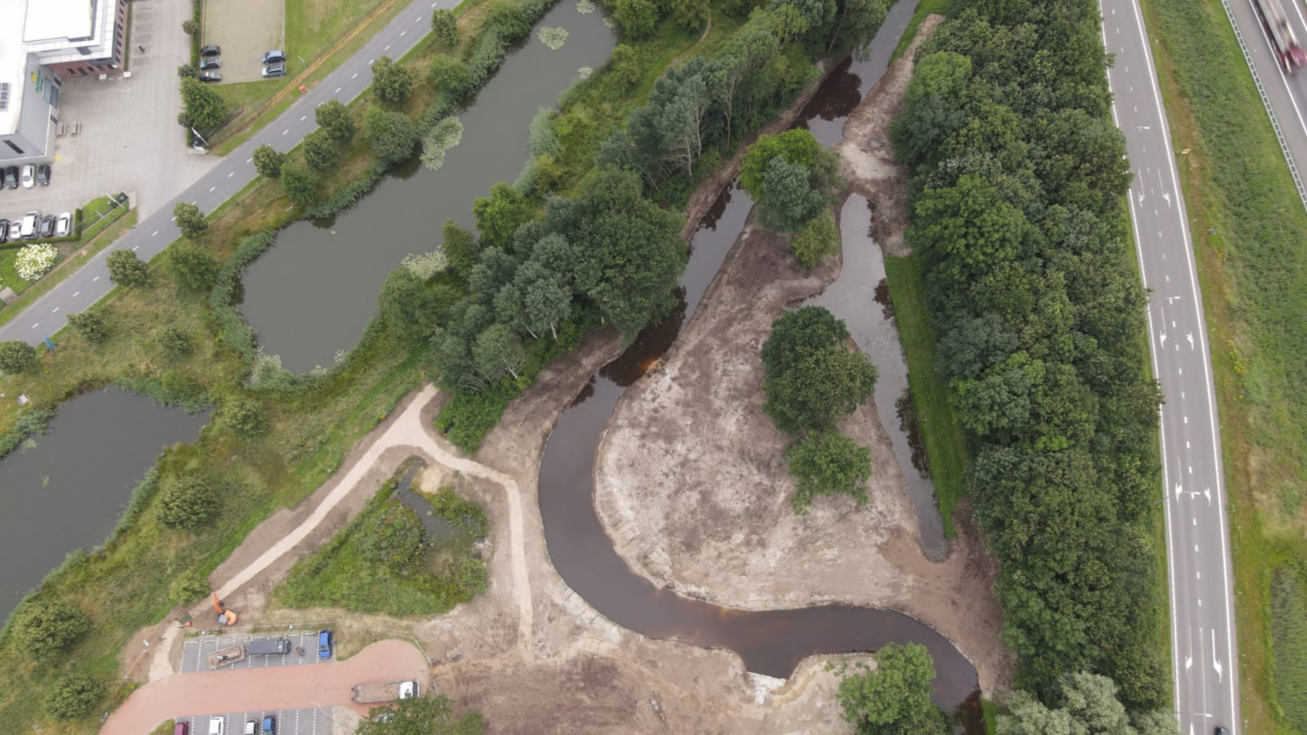 Bovenaanzicht van natuurgebied met de Groote Molenbeek, bomen en een weg