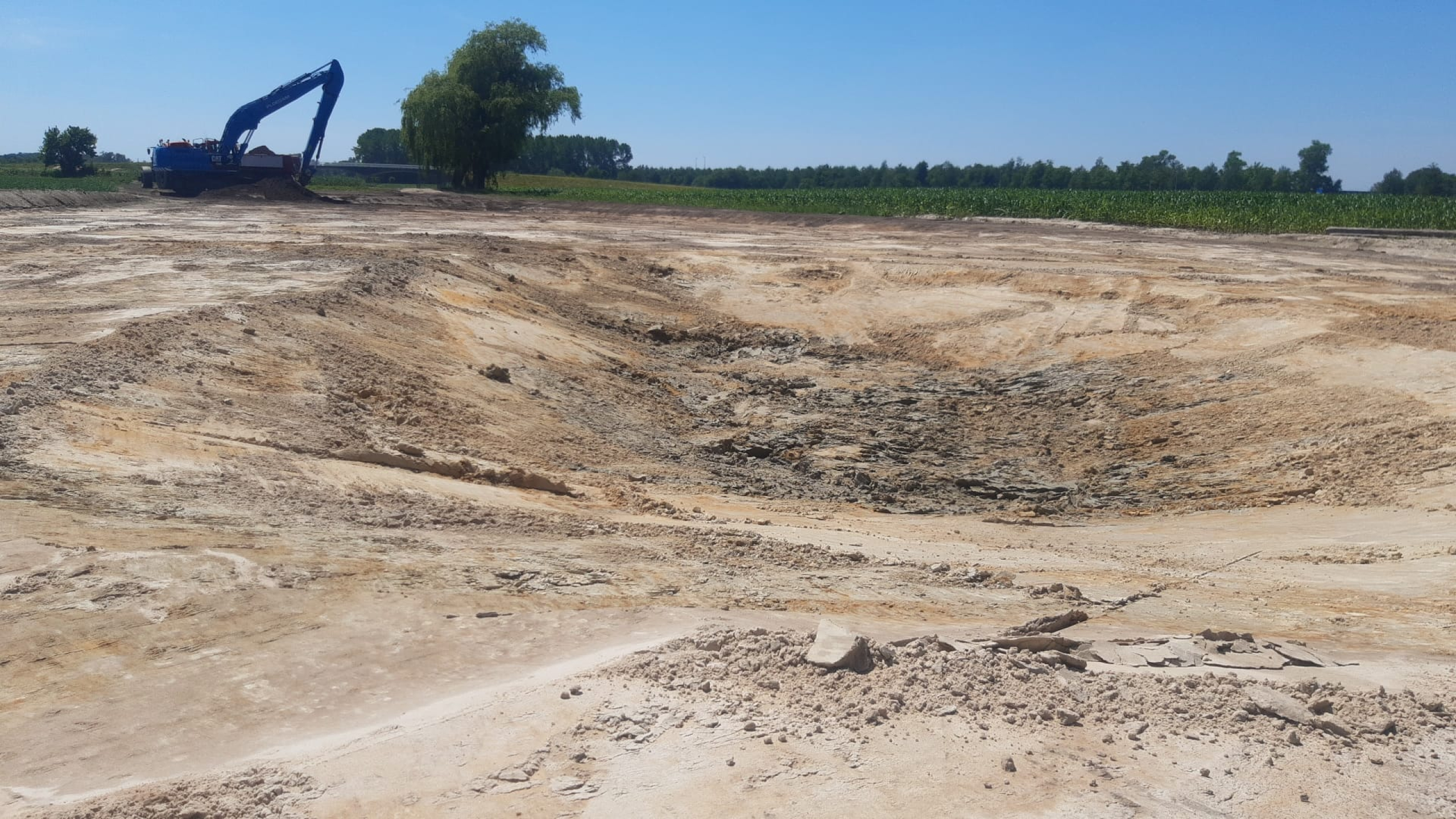 Bouwplaats van zand met een blauwe Ploegam kraan op de achtergrond