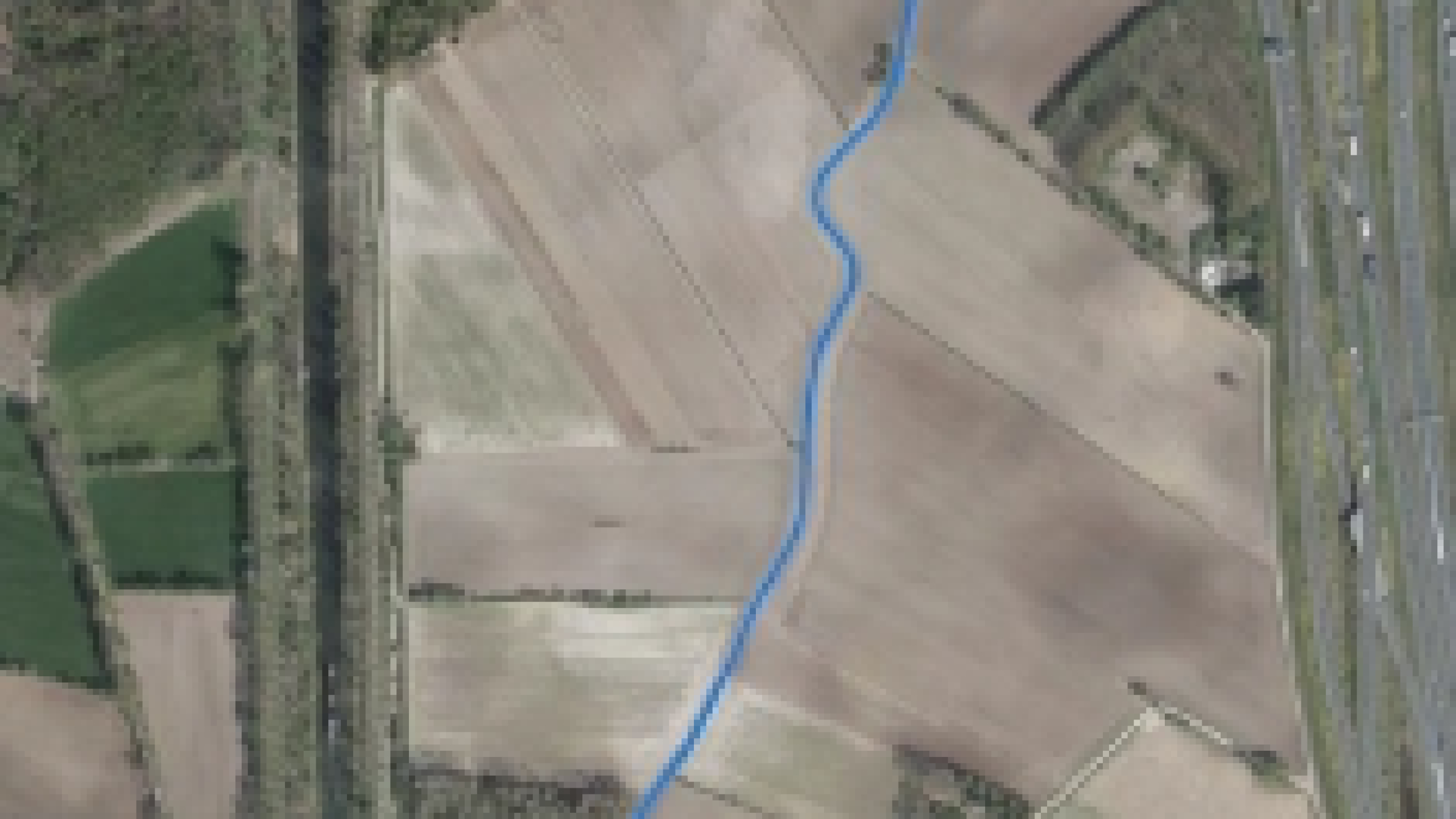 Bovenaanzicht natuurgebied met weilanden en een beek