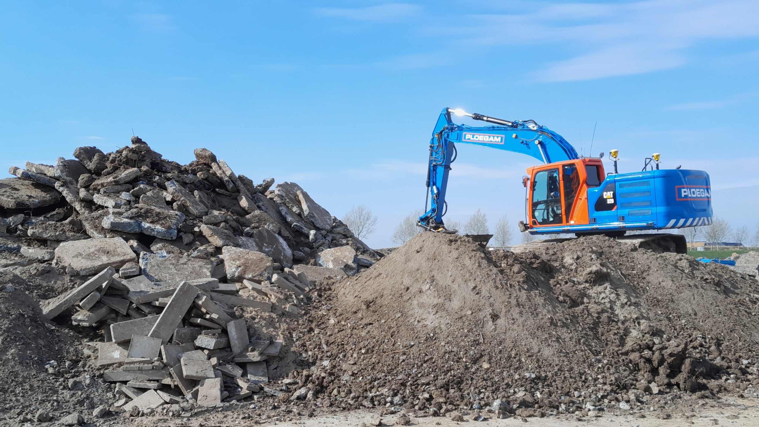 Blauwe Ploegam kraan met zand en puin op de voorgrond