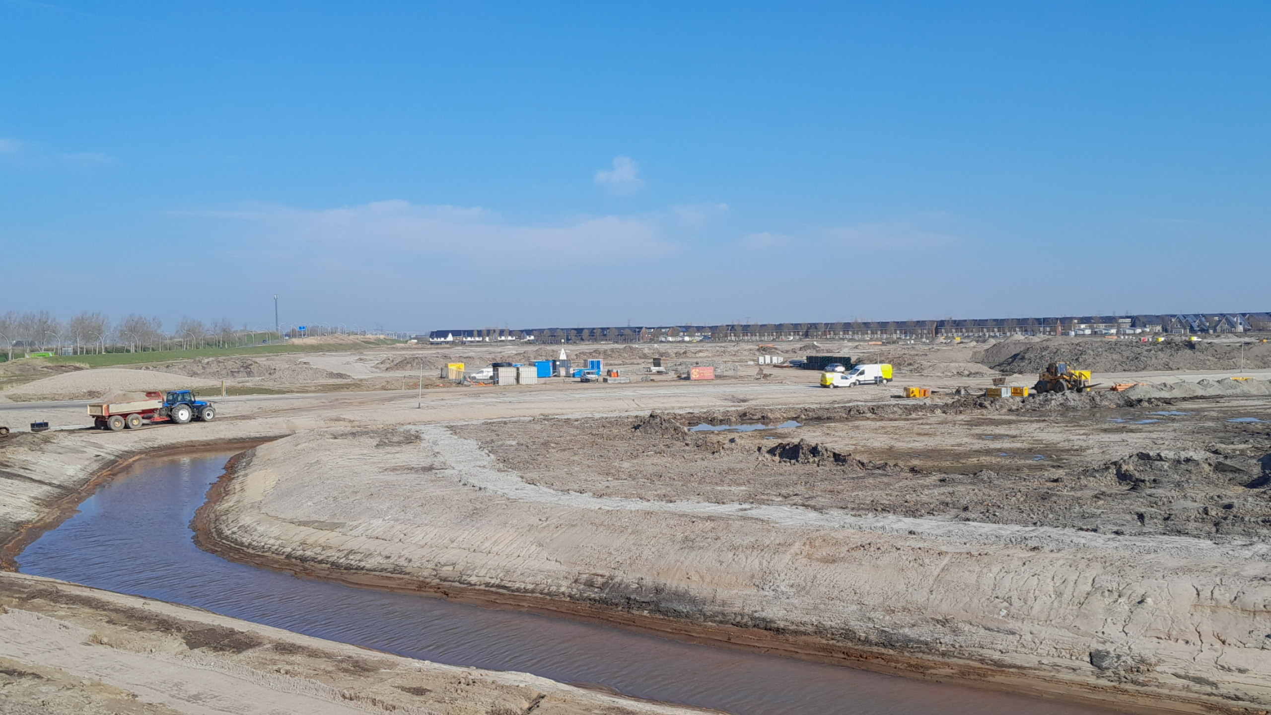 Tractor rijdt in gebied De Tippe over het zand naast een beekje