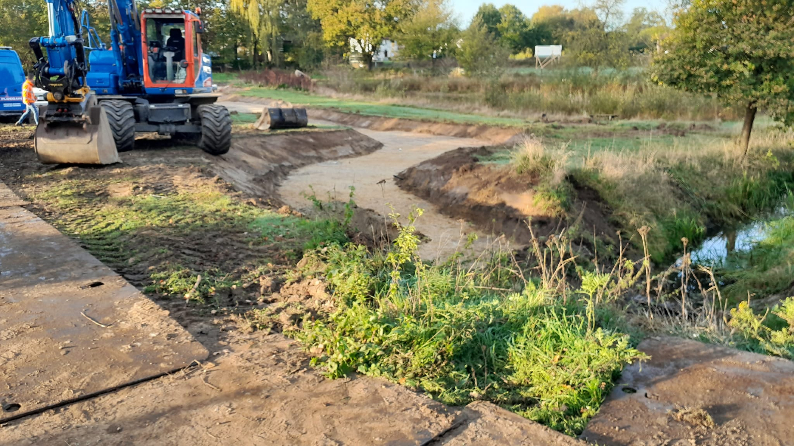 Ploegam kraan in natuurgebied met veel gras en bomen en rijplaten