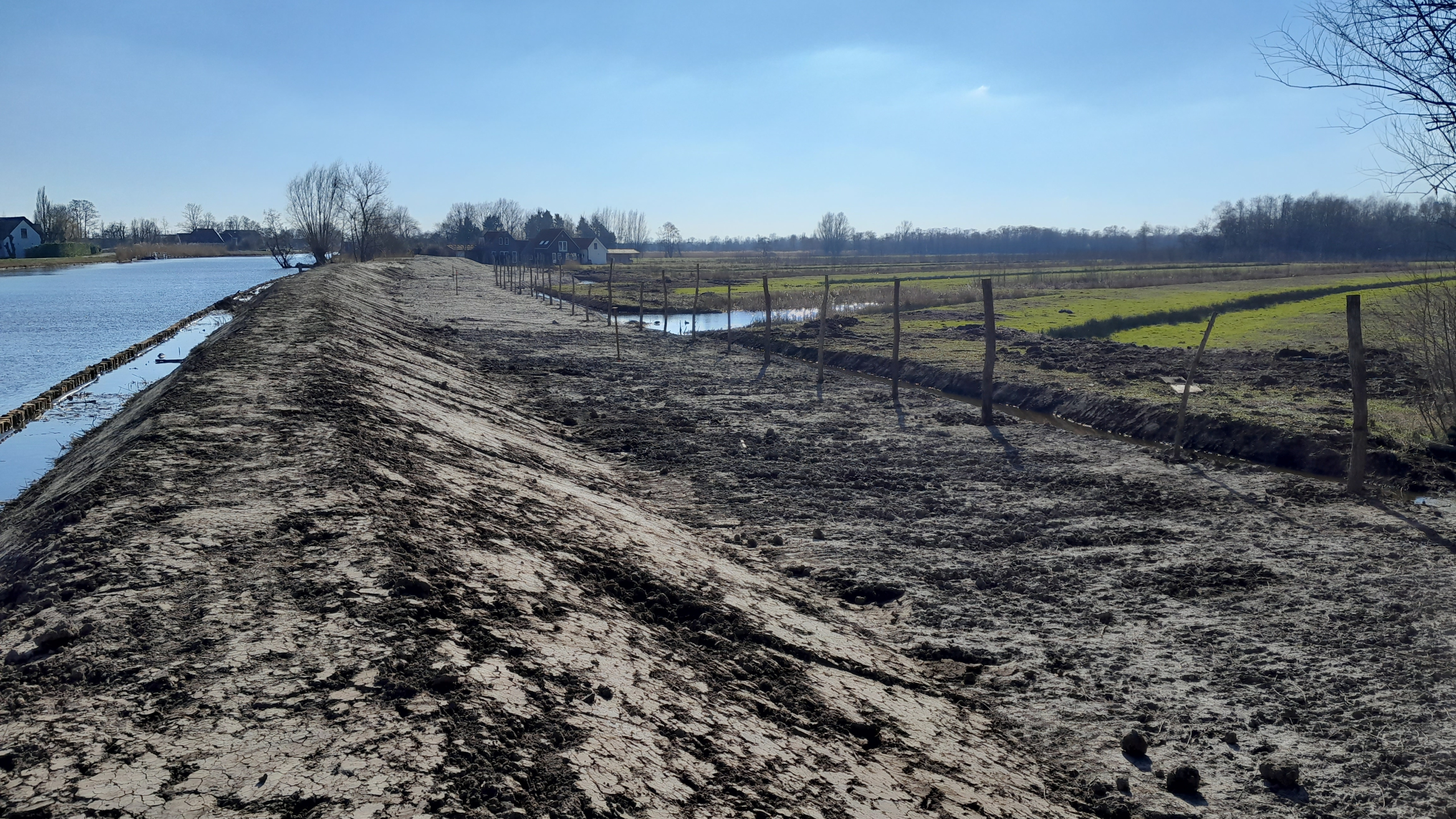 Dijk met zand naast een rivier