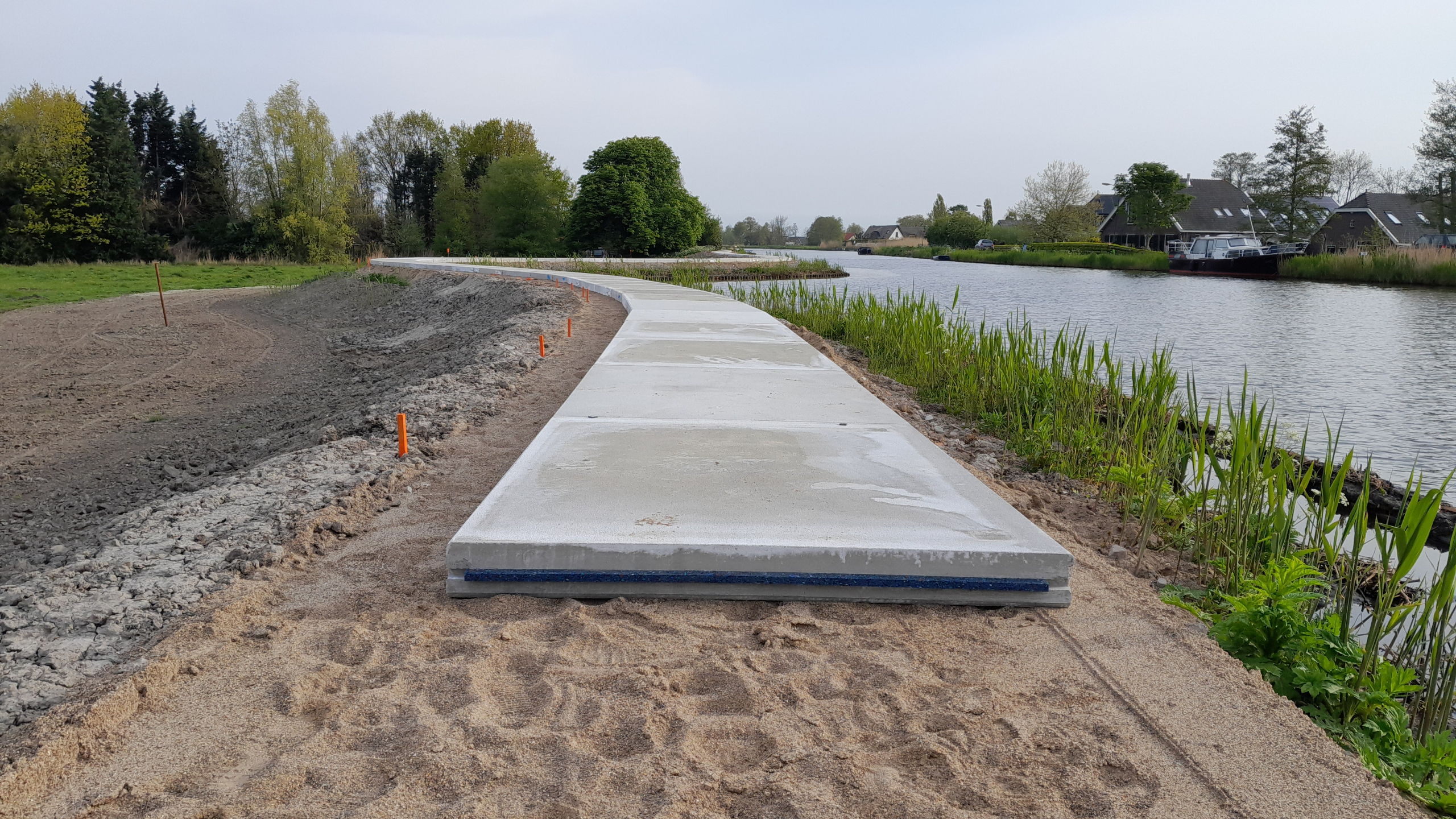 Werkzaamheden fietspad betonnen platen naast rivier