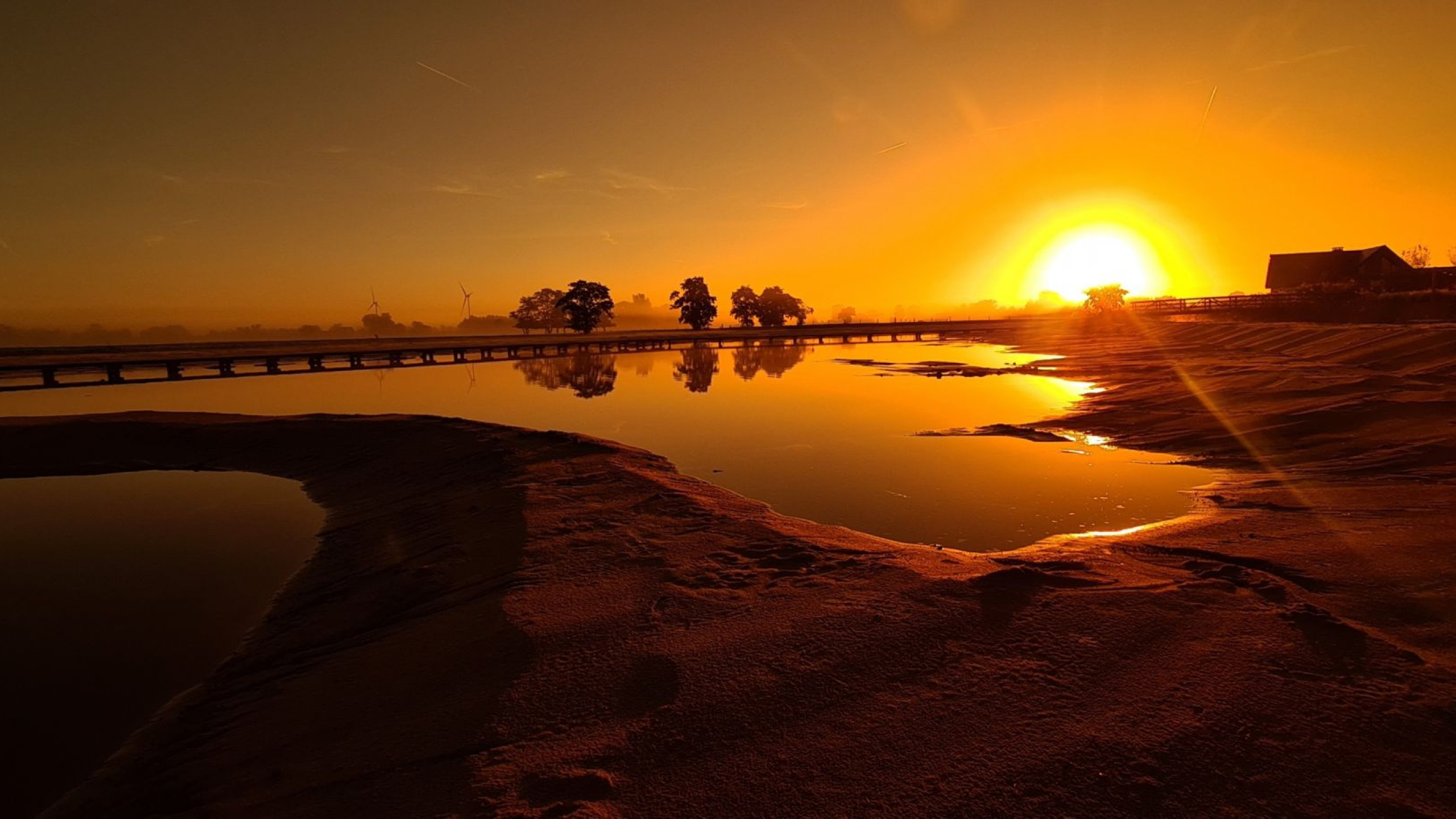 Oranje zonsopgang bij natuurgebied met water en brug