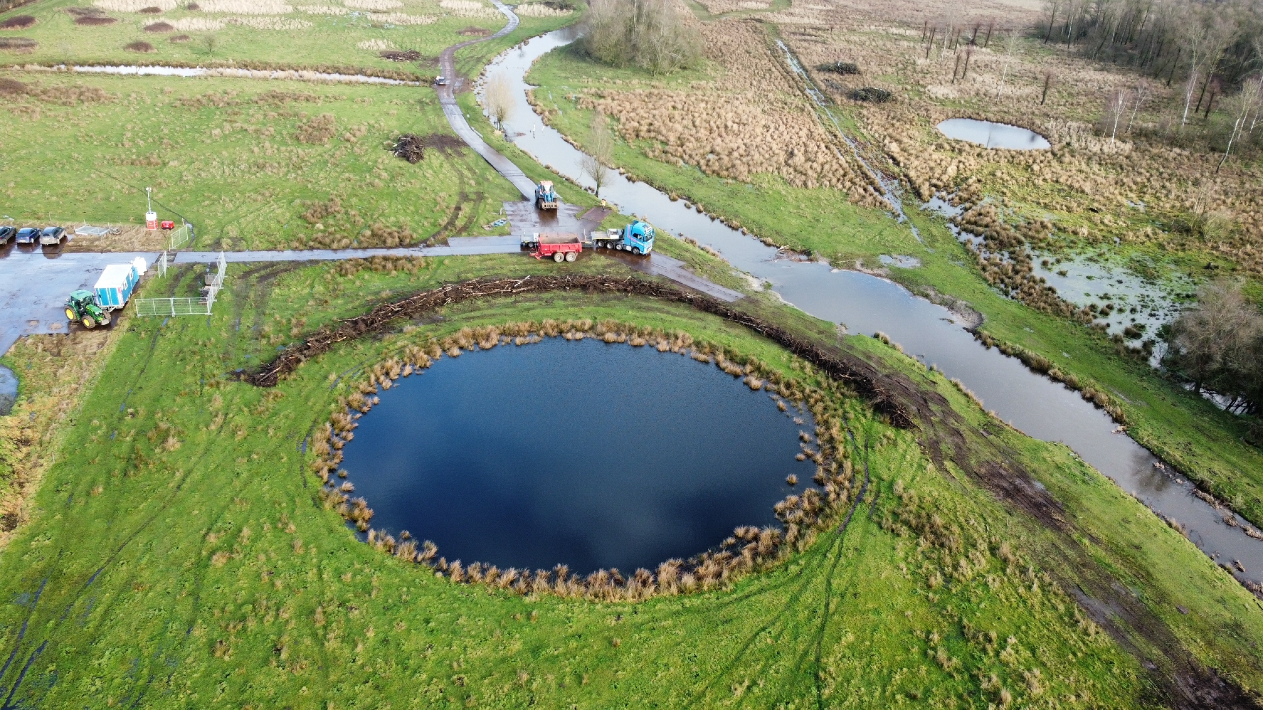 Bovenaanzicht werkzaamheden in natuurgebied met beekjes en een ronde vijver