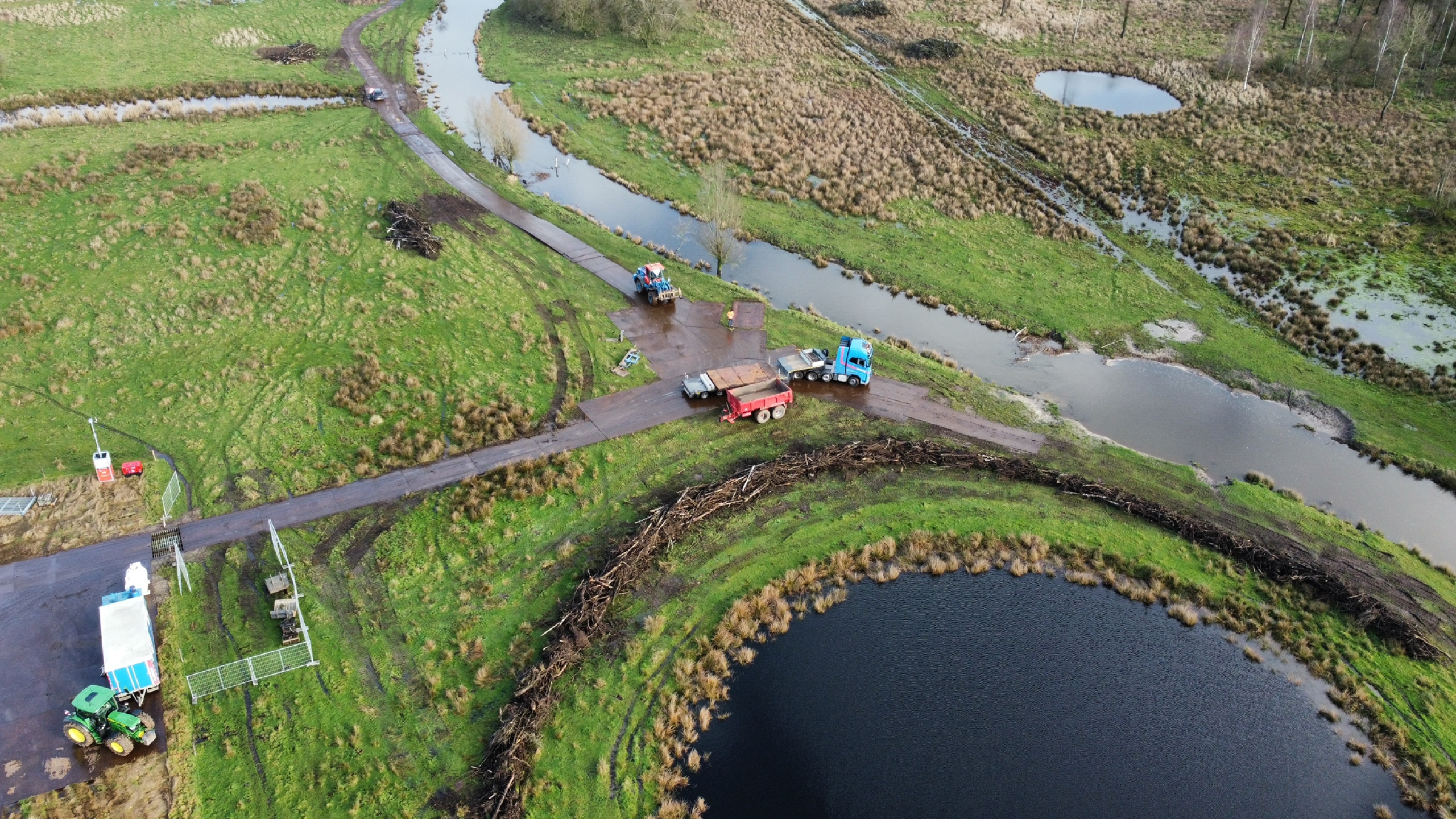 Bovenaanzicht werkzaamheden in natuurgebied met beekjes en een ronde vijver