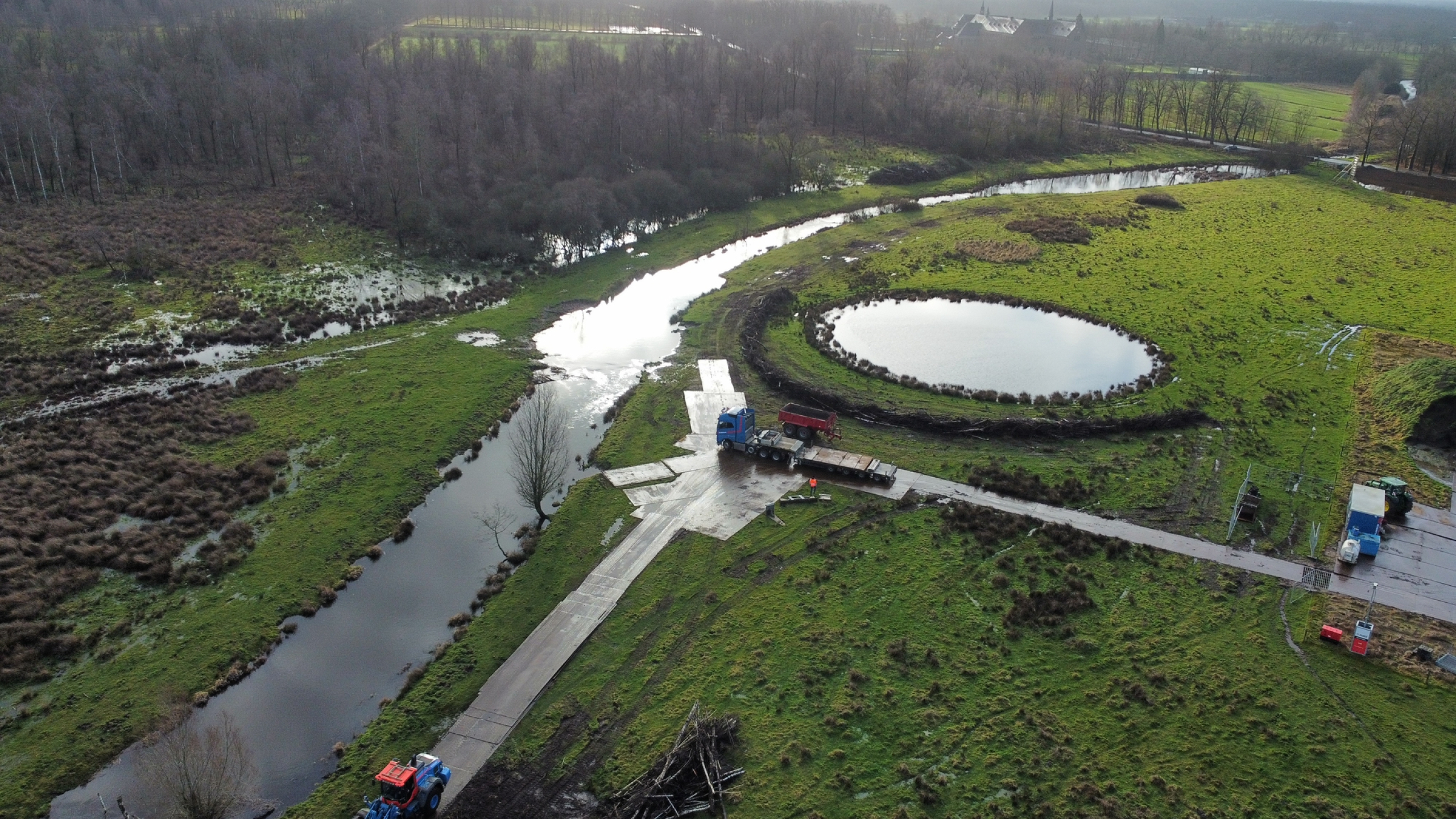 Bovenaanzicht werkzaamheden door Ploegam in natuurgebied met beekjes en een ronde vijver
