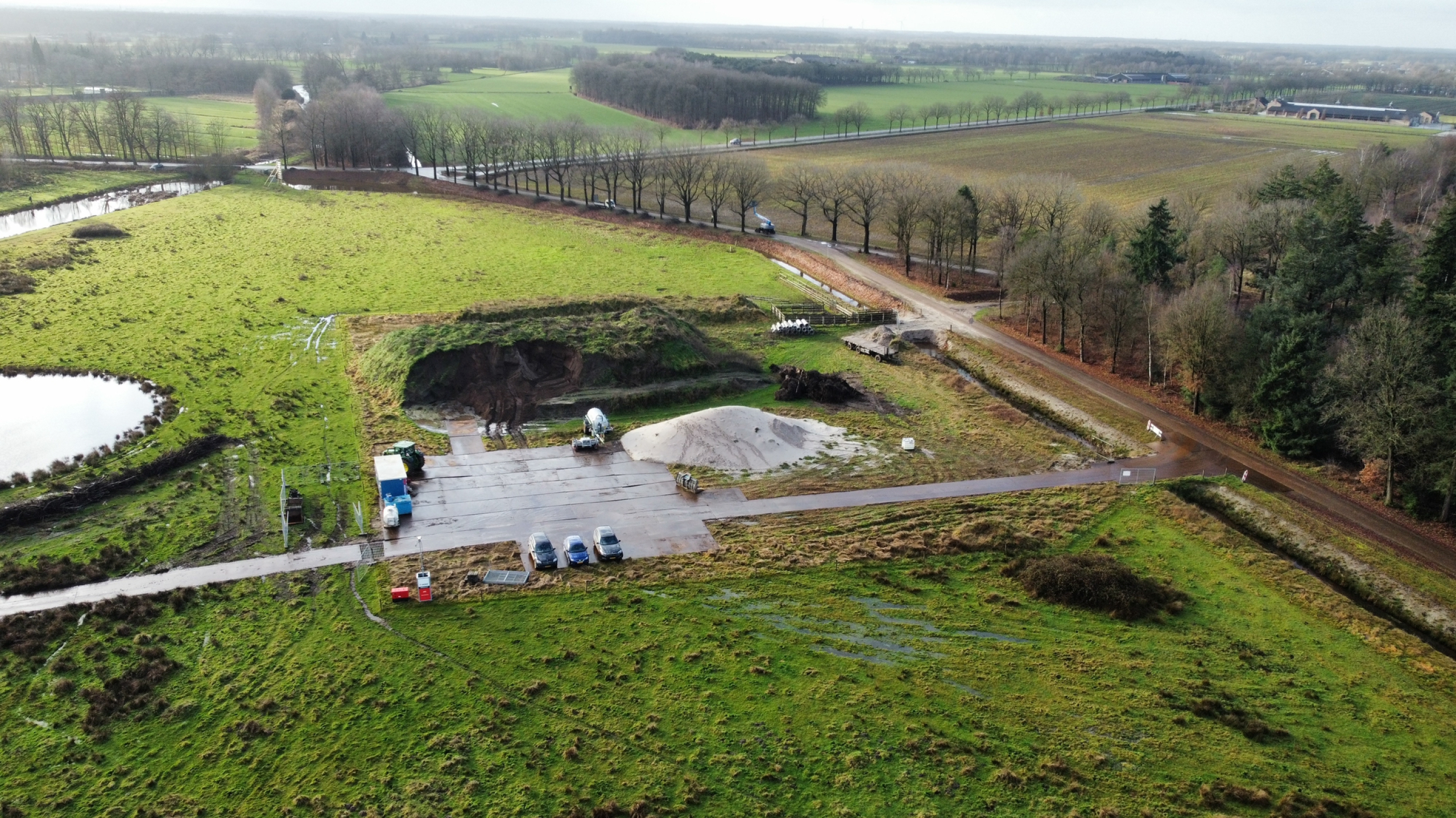 Bovenaanzicht werkzaamheden door Ploegam in natuurgebied met beekjes en een ronde vijver