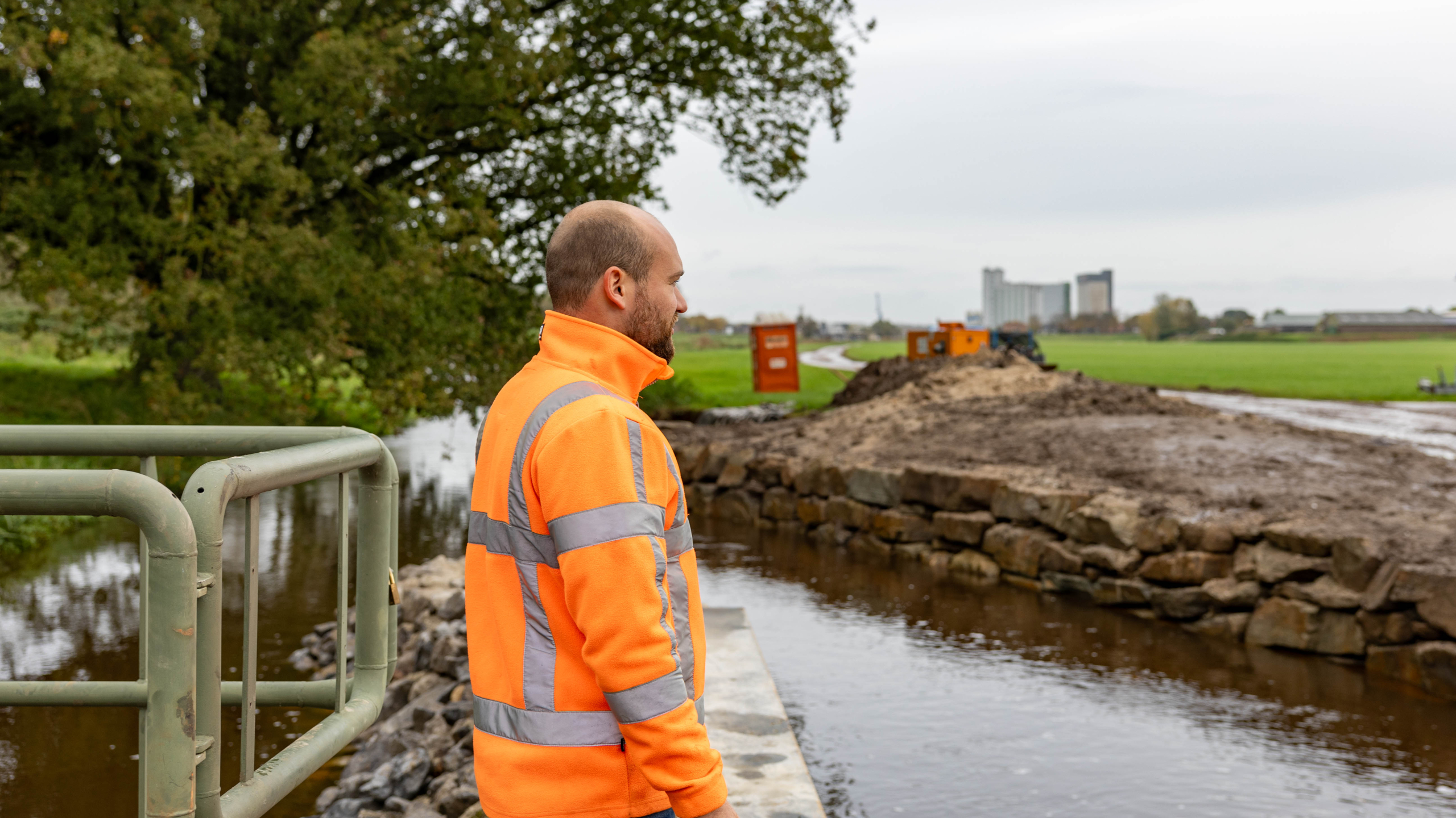 Stapelmuur van grote stenen naast beek met hopen zand en stenen op de achtergrond
