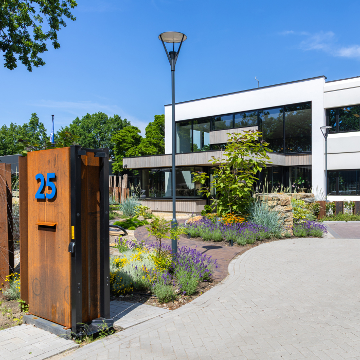 Voorgevel van een spiegelend glazen gebouw met blauwe zuil