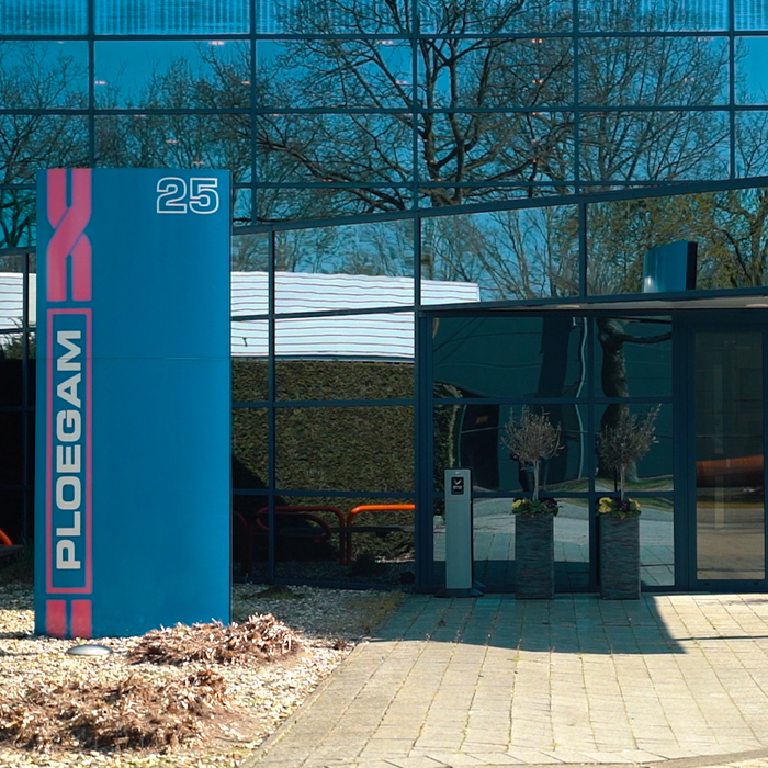 Voorgevel van een spiegelend glazen gebouw met blauwe zuil