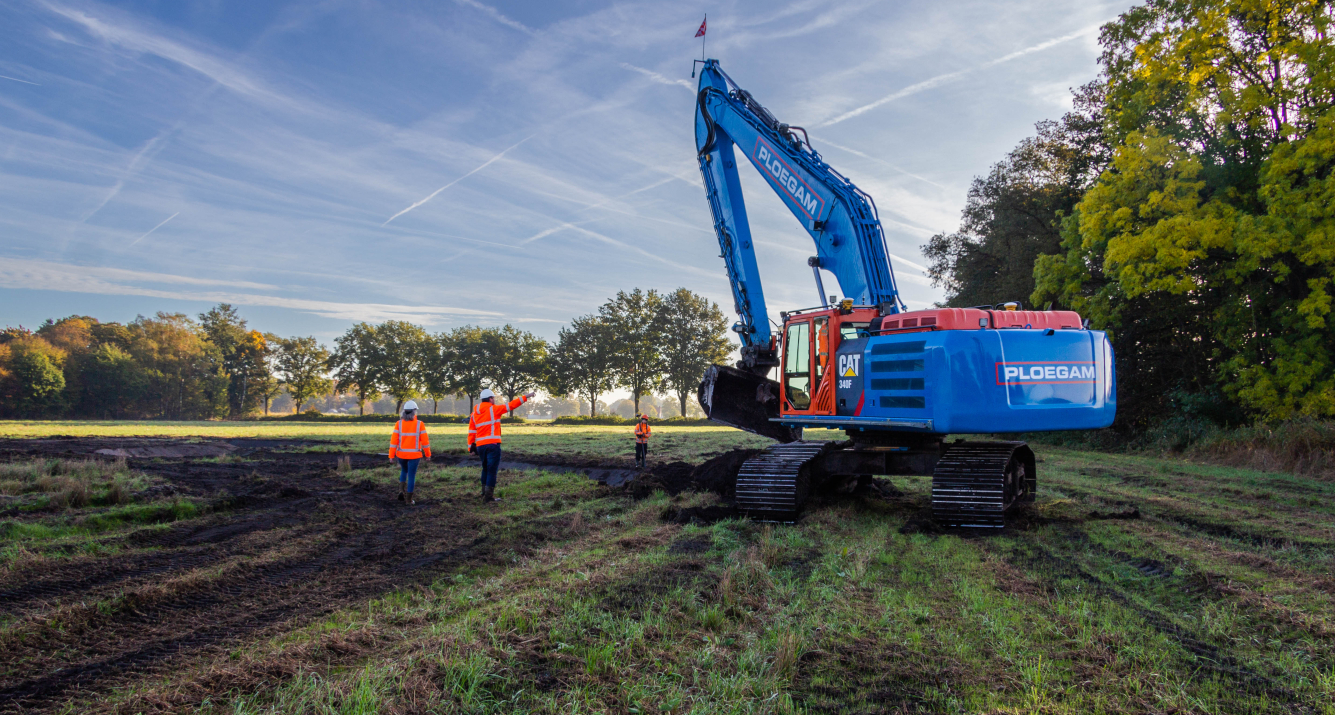 Personen met oranje jassen naast een blauwe Ploegam kraan in natuurgebied