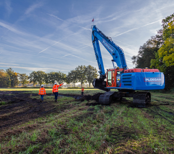 Personen met oranje jassen naast een blauwe Ploegam kraan in natuurgebied